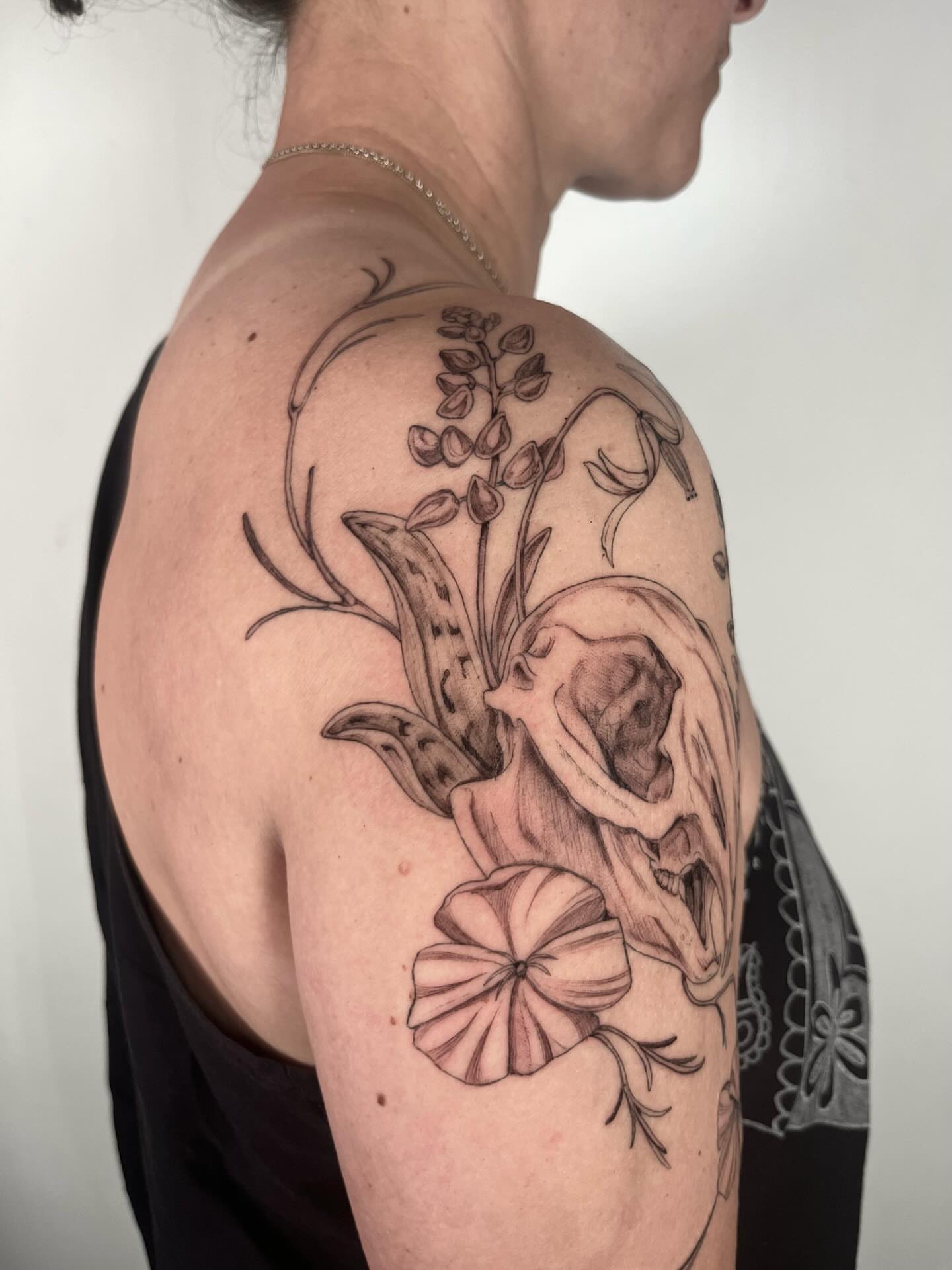 Skull and flowers realism tattoo on the shoulder by Sierra Skye
