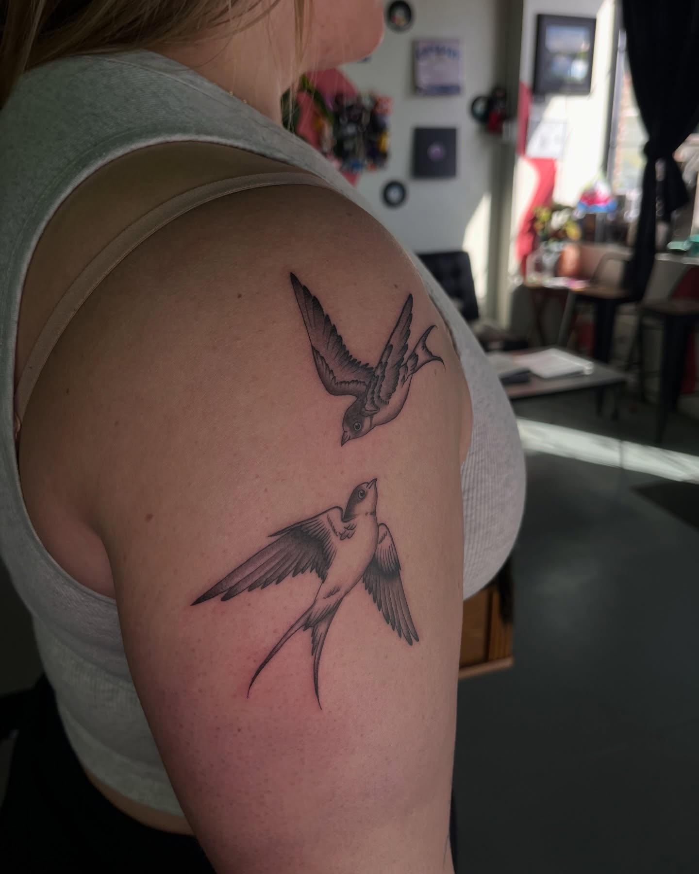 Swallows black and grey tattoo on the shoulder by Daniela