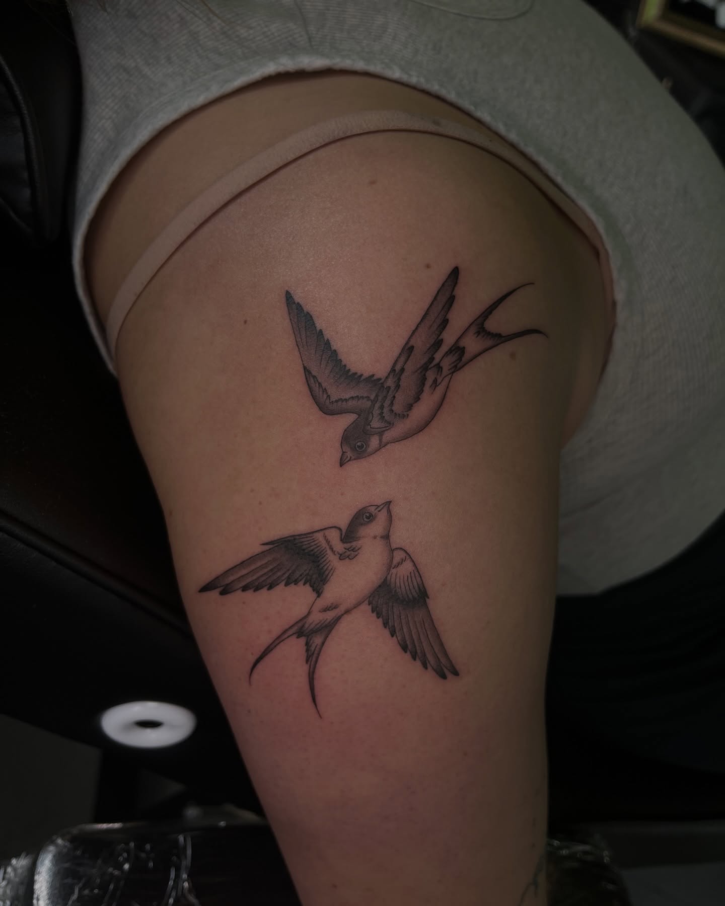 Swallows black and grey tattoo on the thigh by Daniela