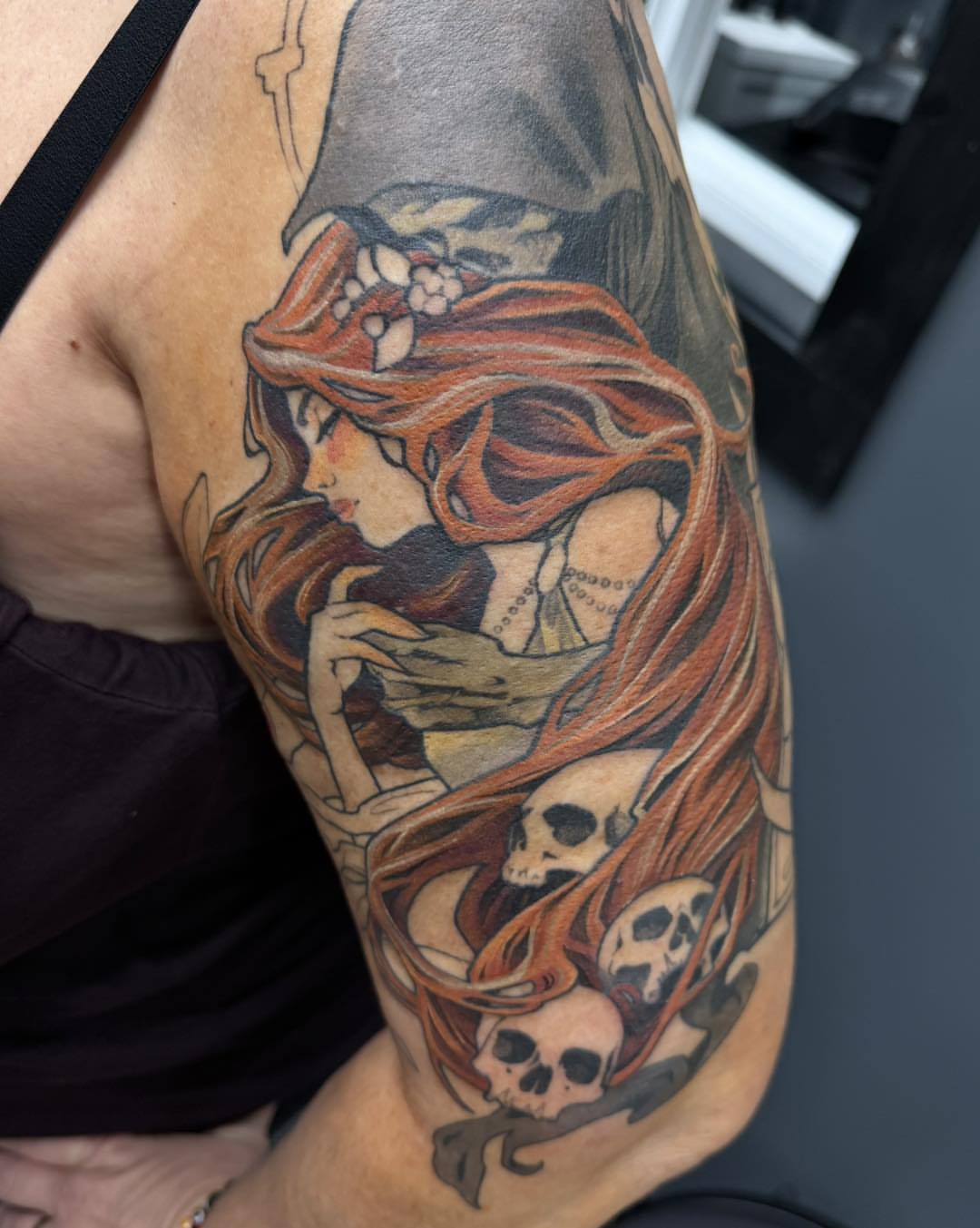 Woman with skulls dark realism tattoo on the upper arm by Harper Clark