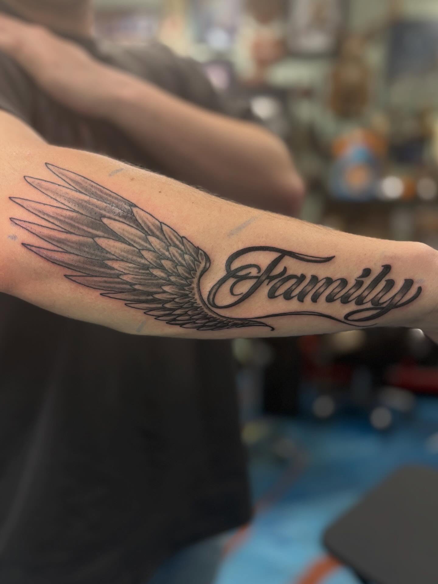Family black and grey tattoo on the forearm by Cam Sykes