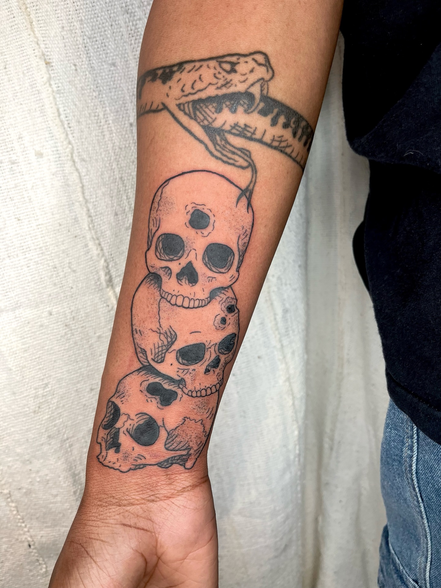 Skulls and snake black and grey tattoo on the forearm by Maris Hare, Philadelphia, Pennsylvania