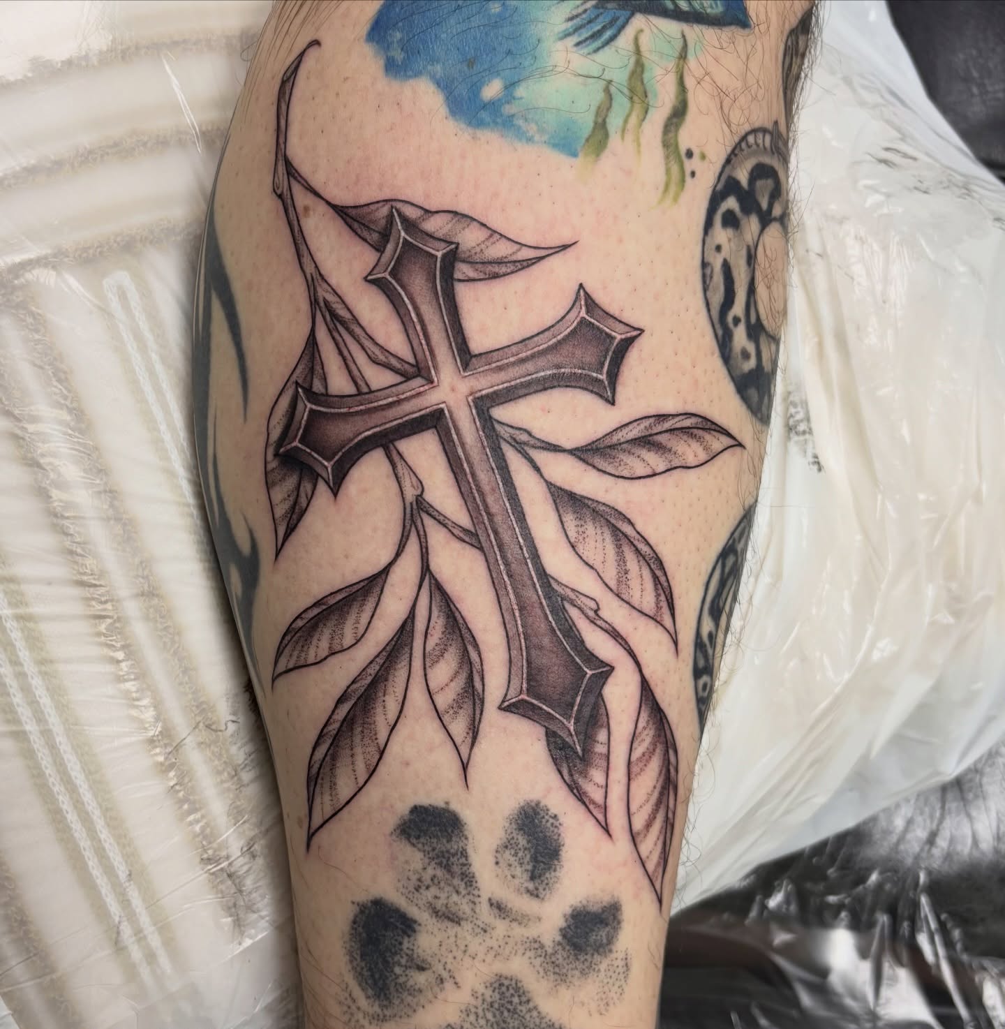 Cross with leaves black and grey tattoo on the forearm by sydney honn