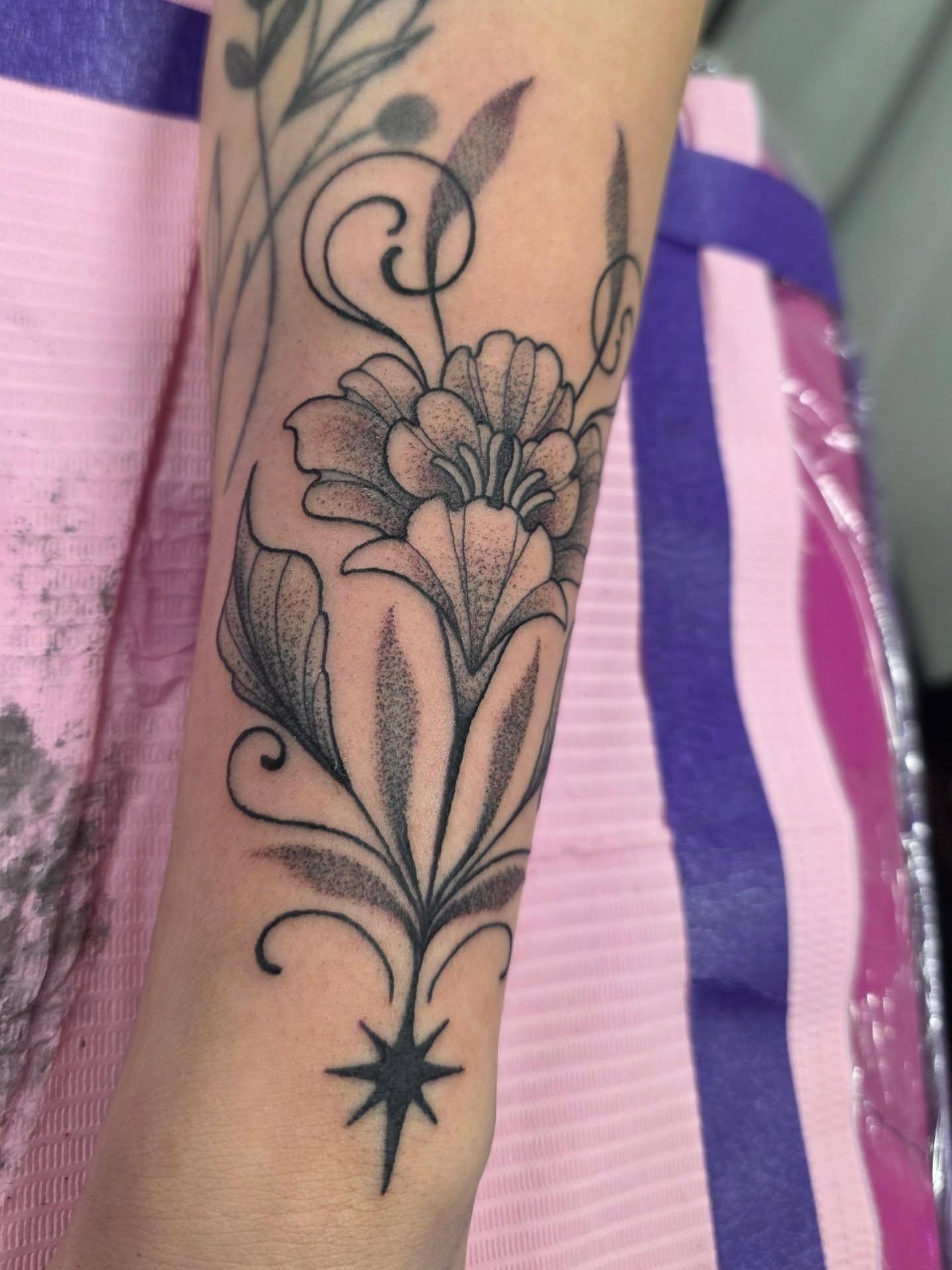 Flower and star black and grey tattoo on the forearm by Mandy Rizzuto