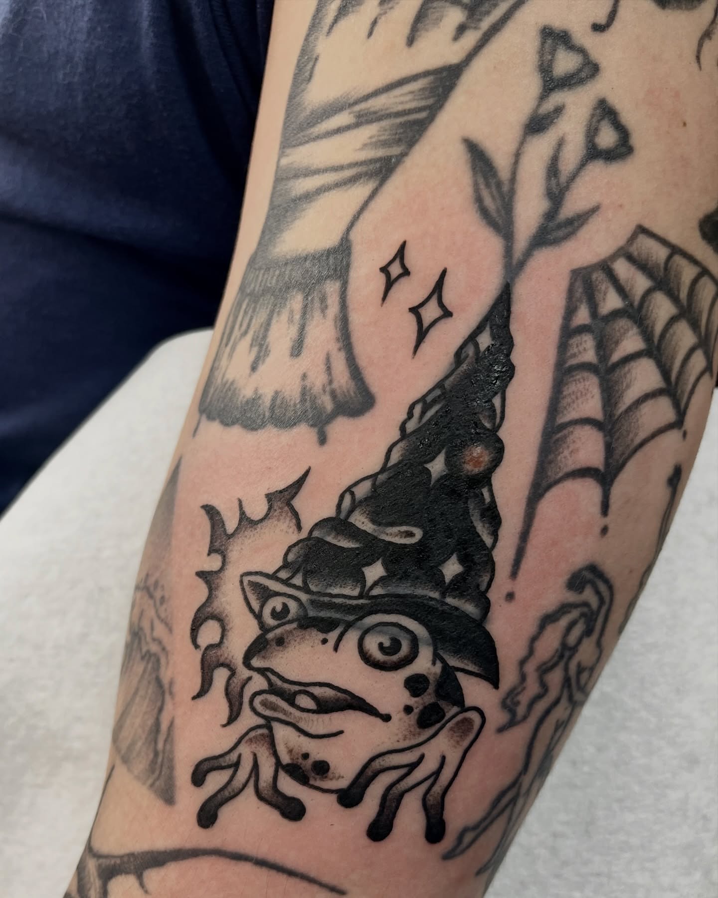 Frog with hat black and grey tattoo on the forearm by jay