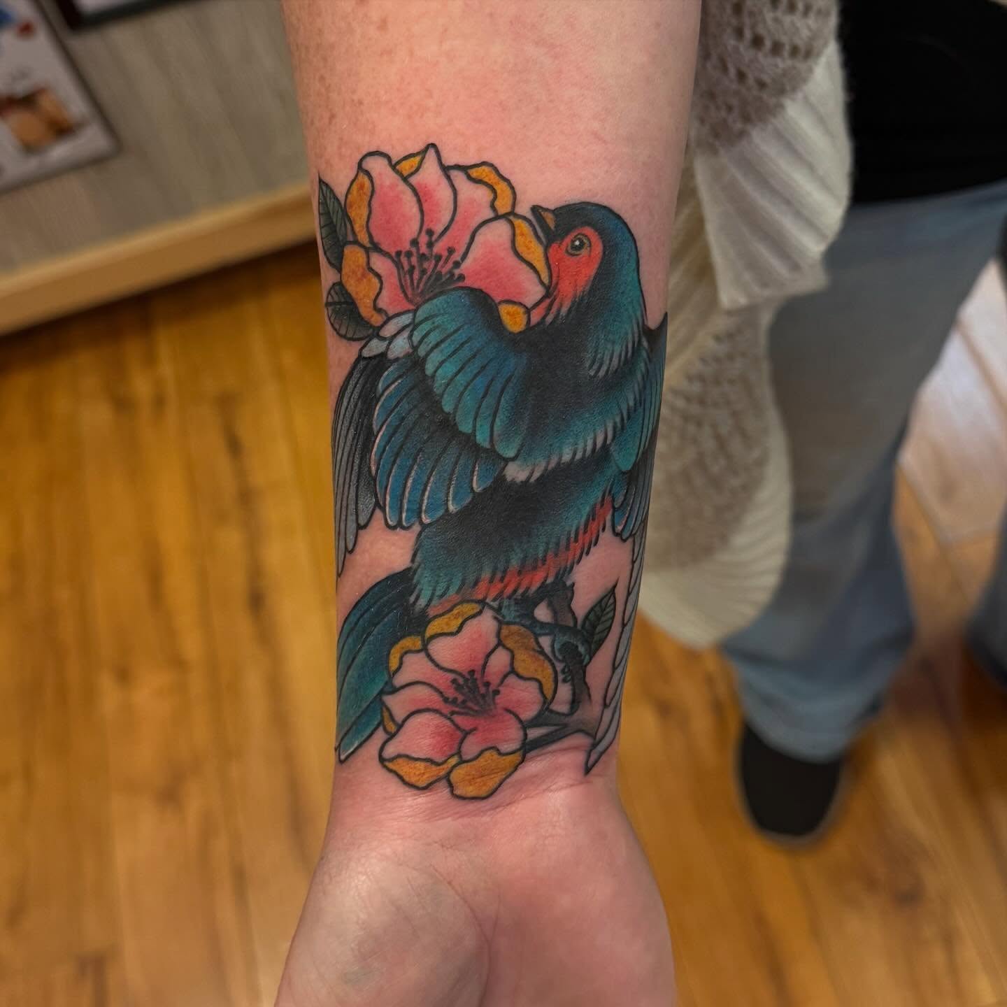 Bird and flowers American traditional tattoo on the forearm by Madilynn Klassen