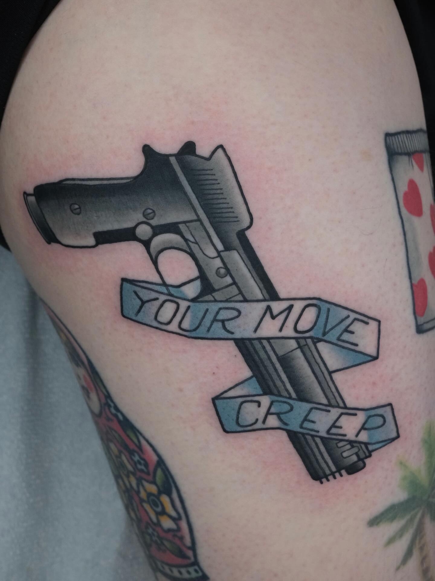 Gun and banner black and grey tattoo on the thigh by James Maxwell