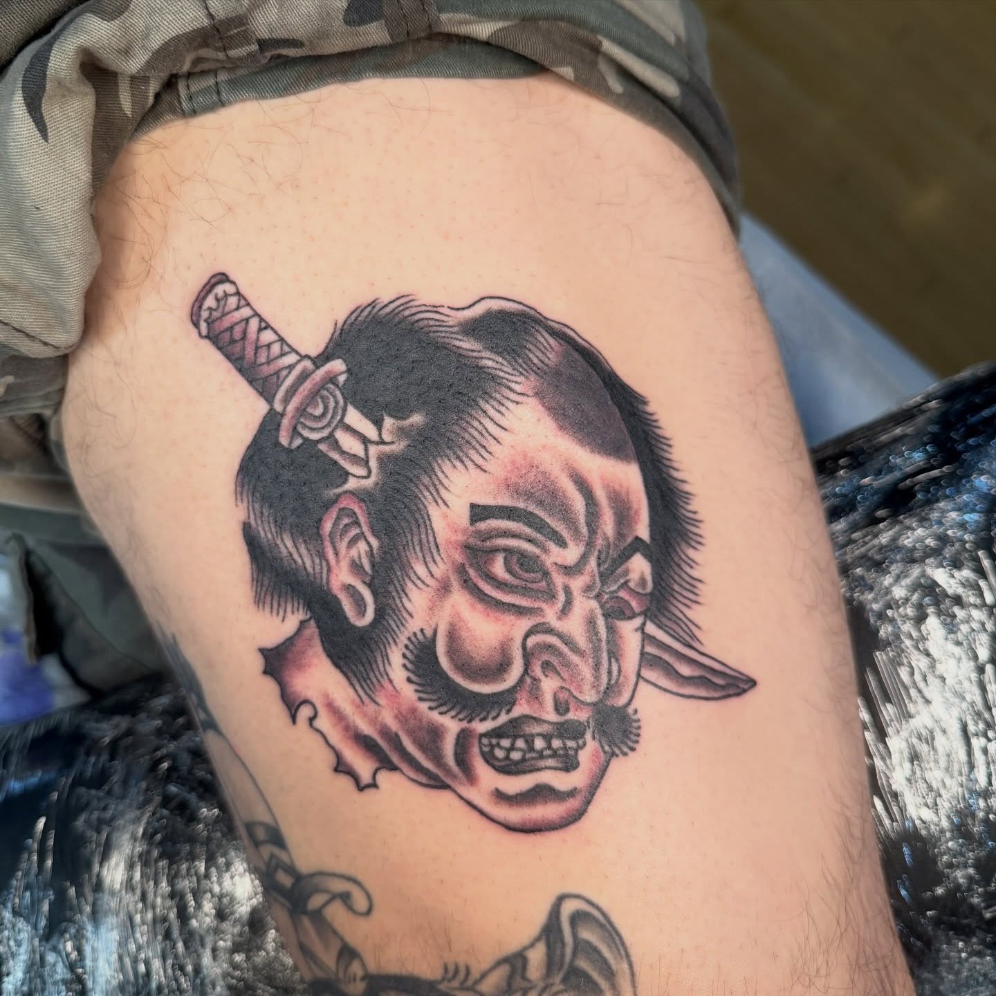 Japanese mask American traditional tattoo on the thigh by Trevor Berry