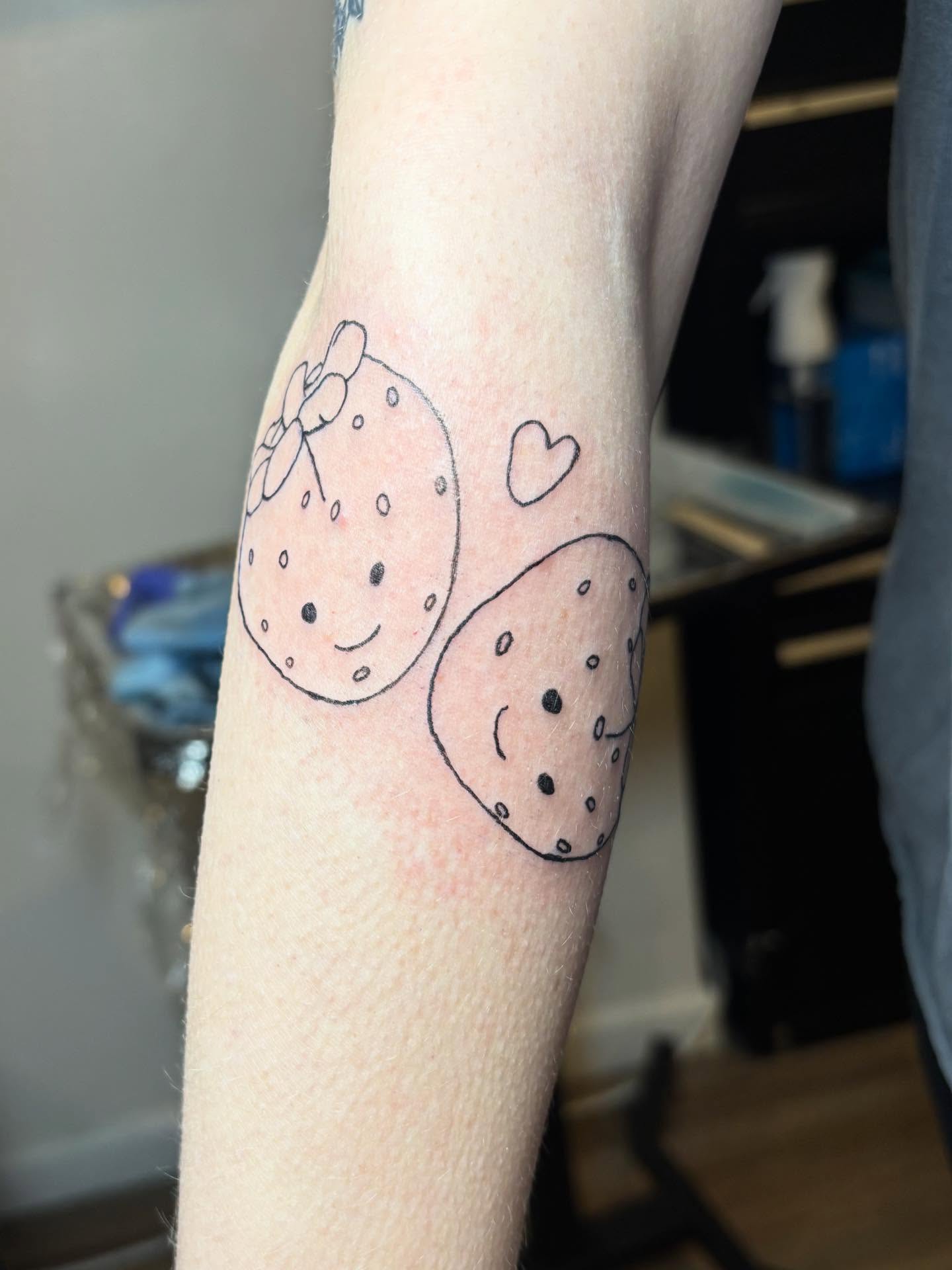 Strawberry and cookie dotwork tattoo on the forearm by riley