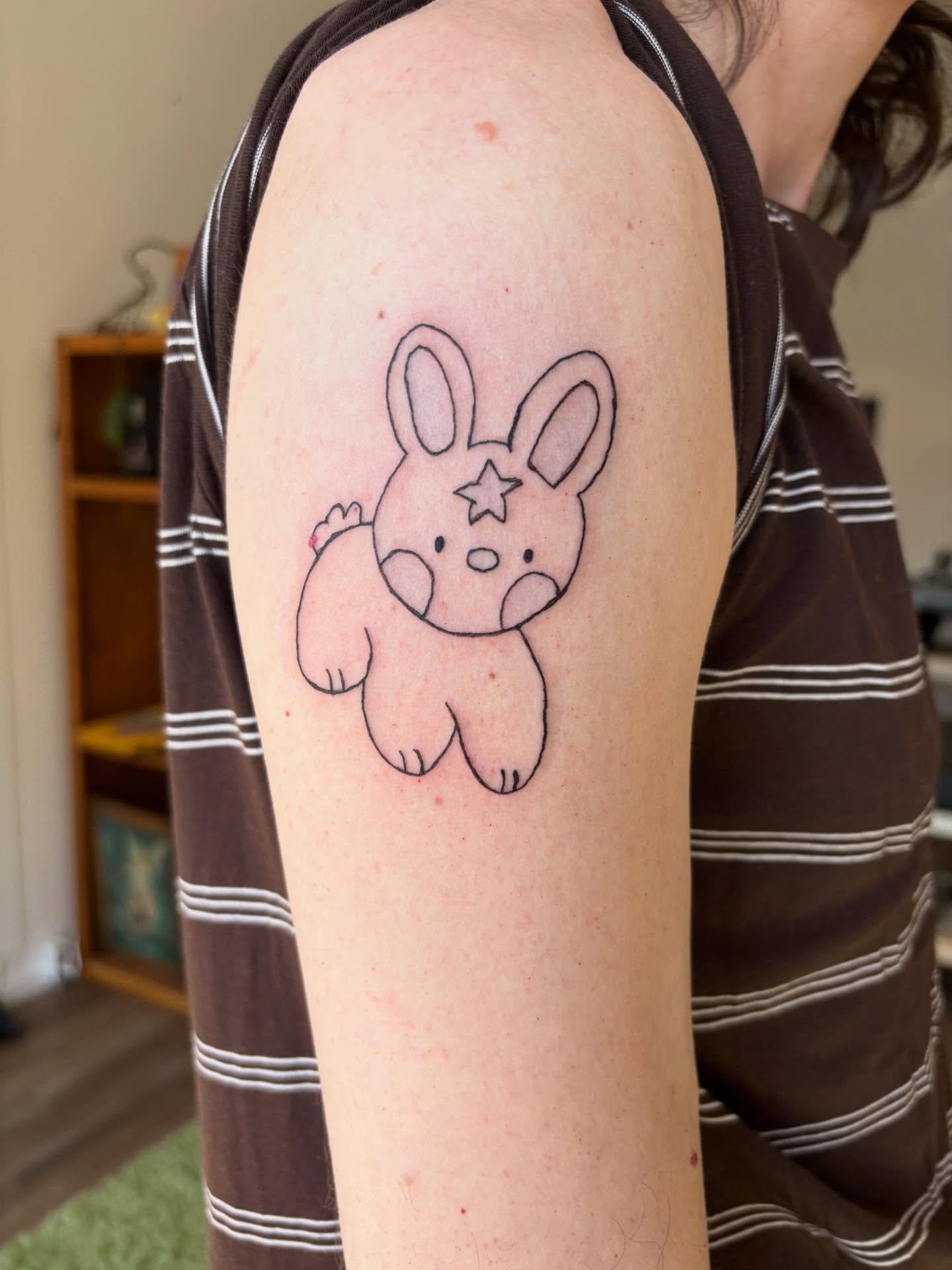 Rabbit minimalist tattoo on the upper arm by riley