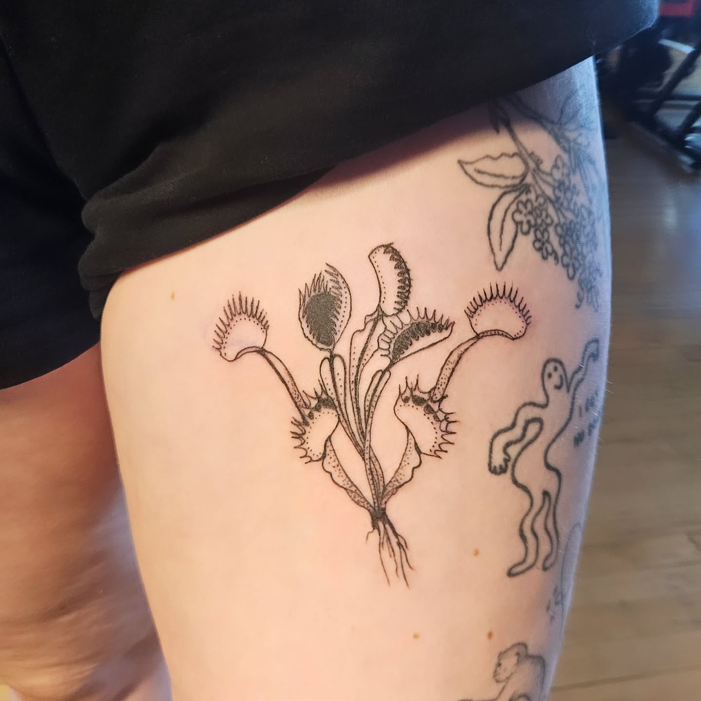 Venus flytrap black and grey tattoo on the thigh by Ammy