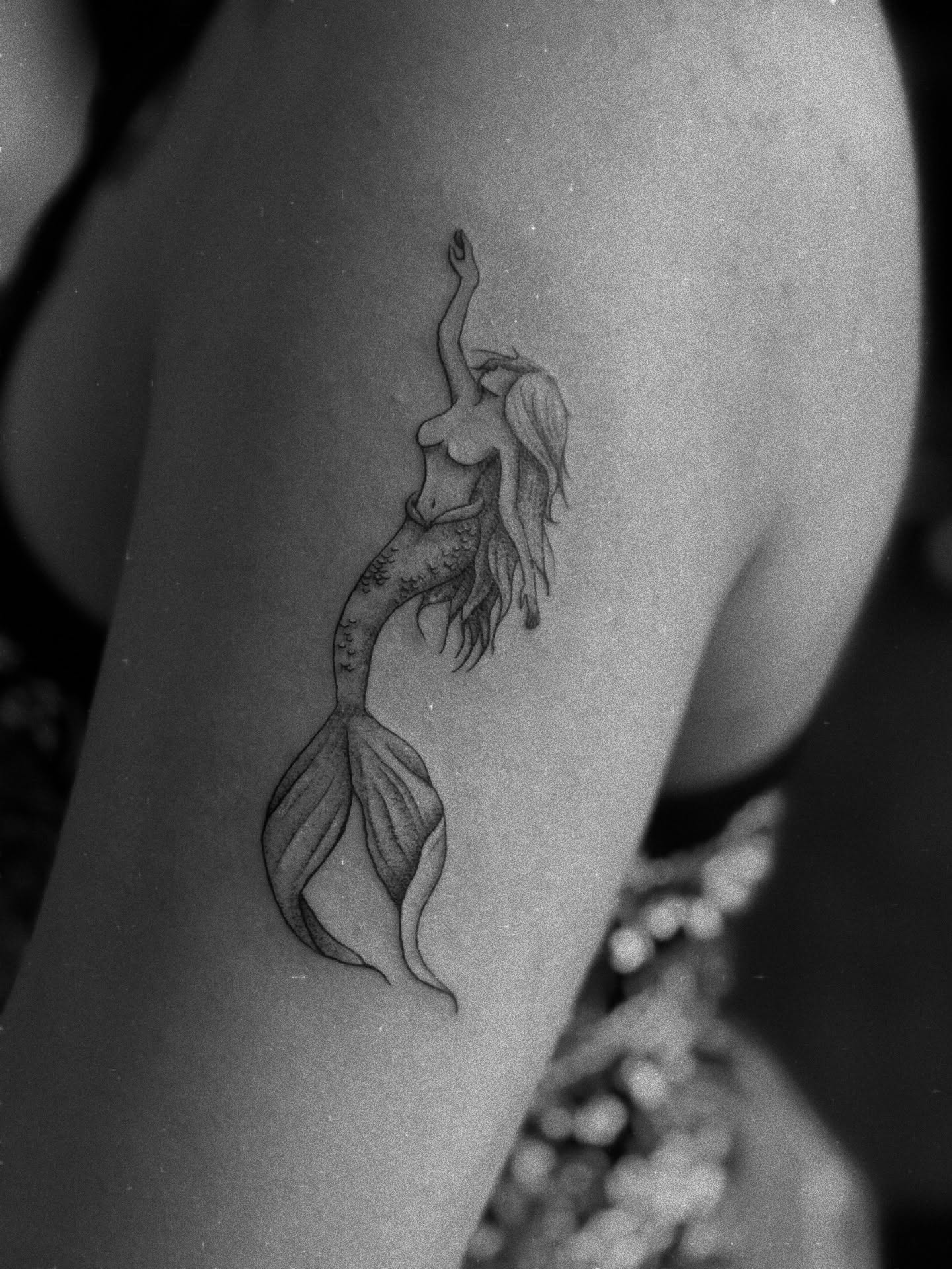 Mermaid black and grey tattoo on the upper arm by Gianna G