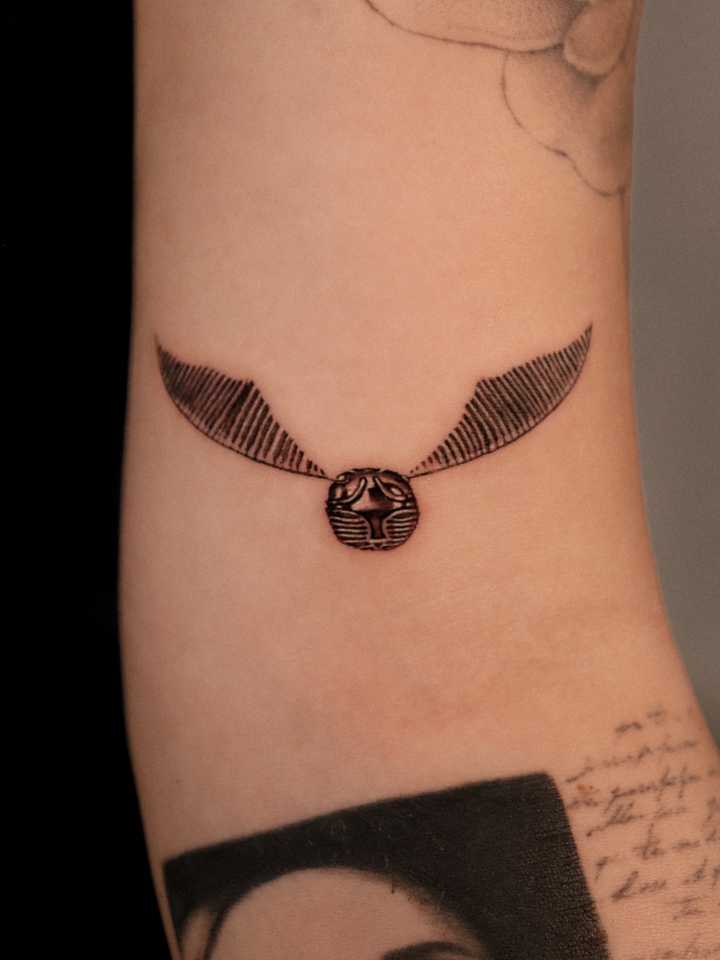Golden snitch black and grey tattoo on the forearm by Joy Christiana