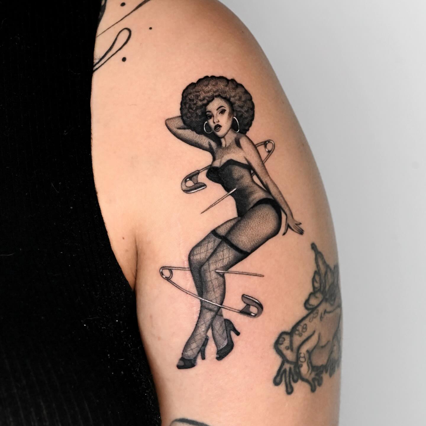 Pin-up girl black and grey tattoo on the upper arm by dom