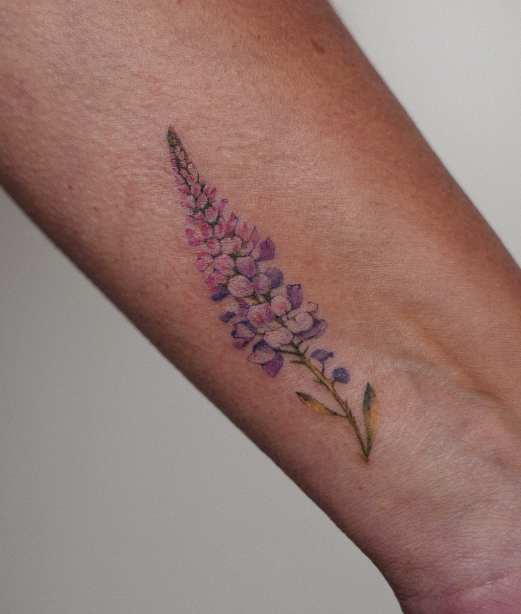 Flower watercolor tattoo on the forearm by Helly March
