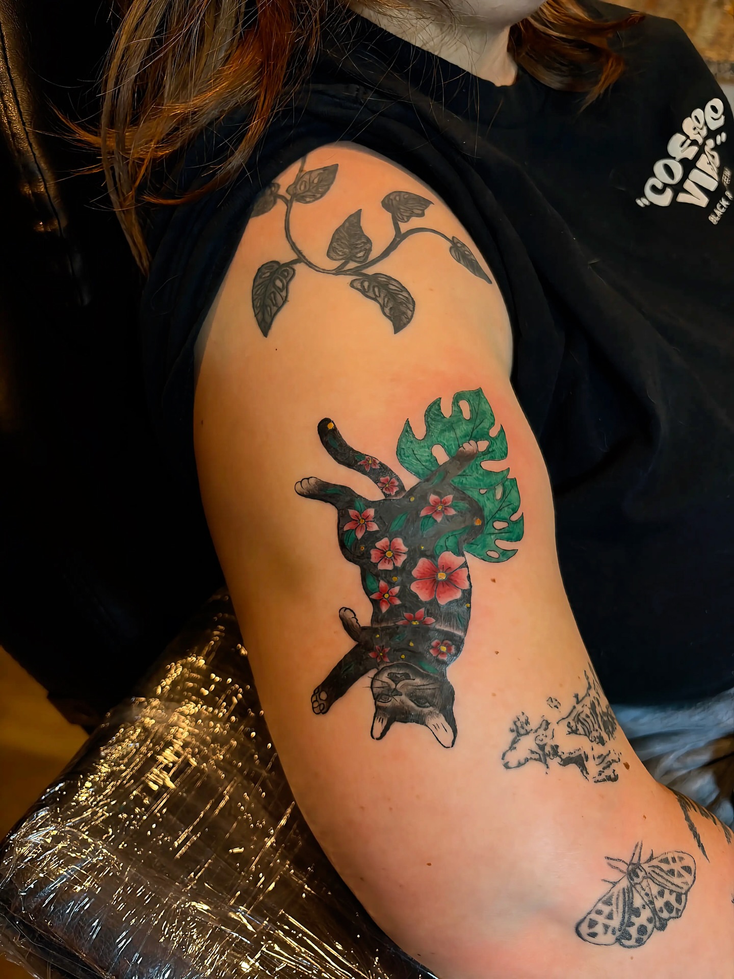 Cat with flowers new school tattoo on the shoulder by Inky Birdz Tattoos