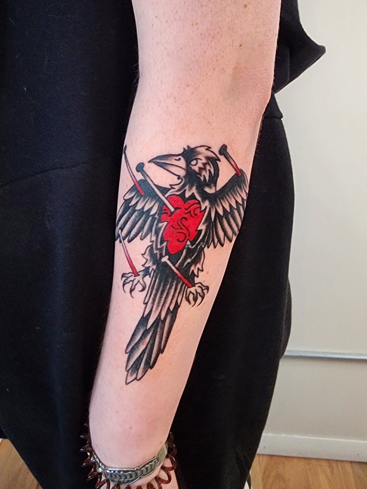 Raven with heart American traditional tattoo on the forearm by Maxine Stewart