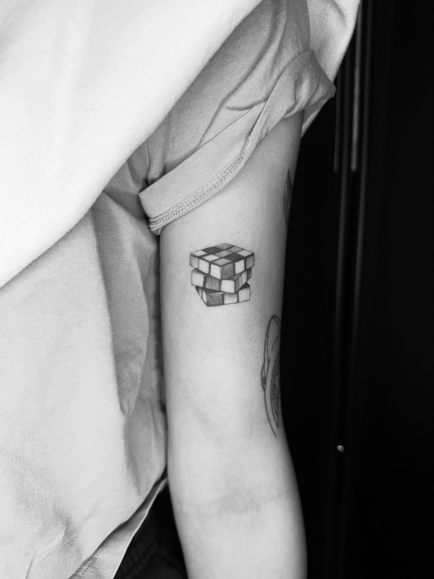 Rubik's cube black and grey tattoo on the forearm by Kait