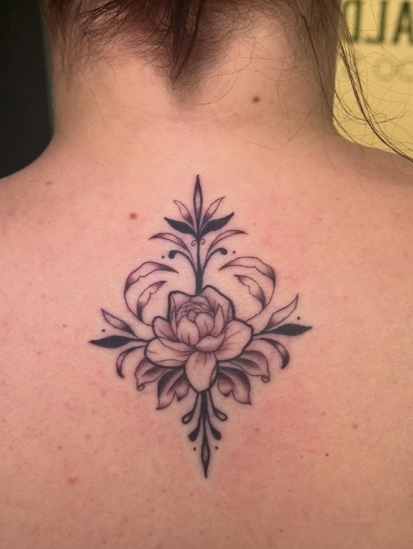 Floral arrangement black and grey tattoo on the back by Madison Pegram