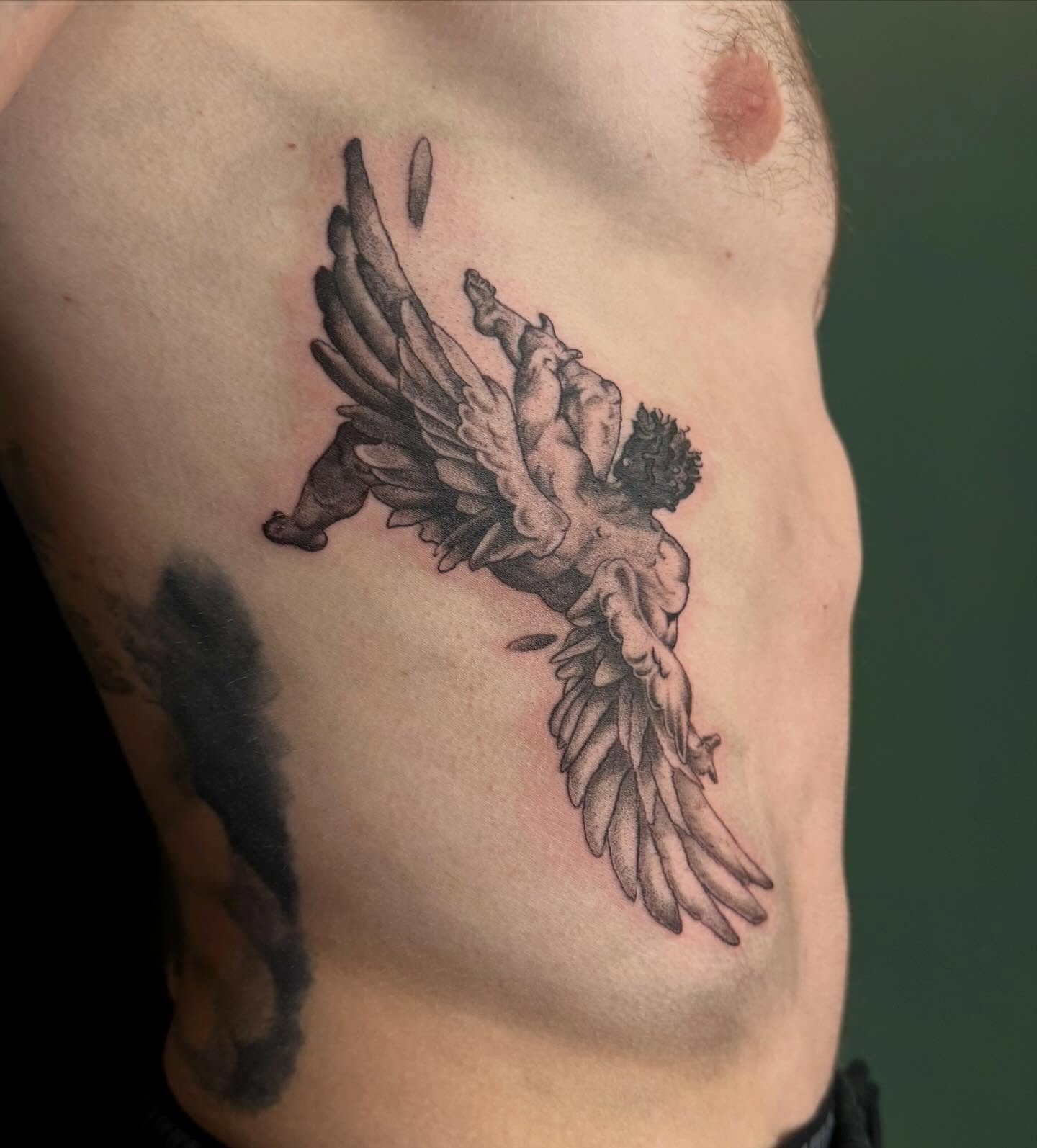 Winged cherub black and grey tattoo on the chest by Bailee