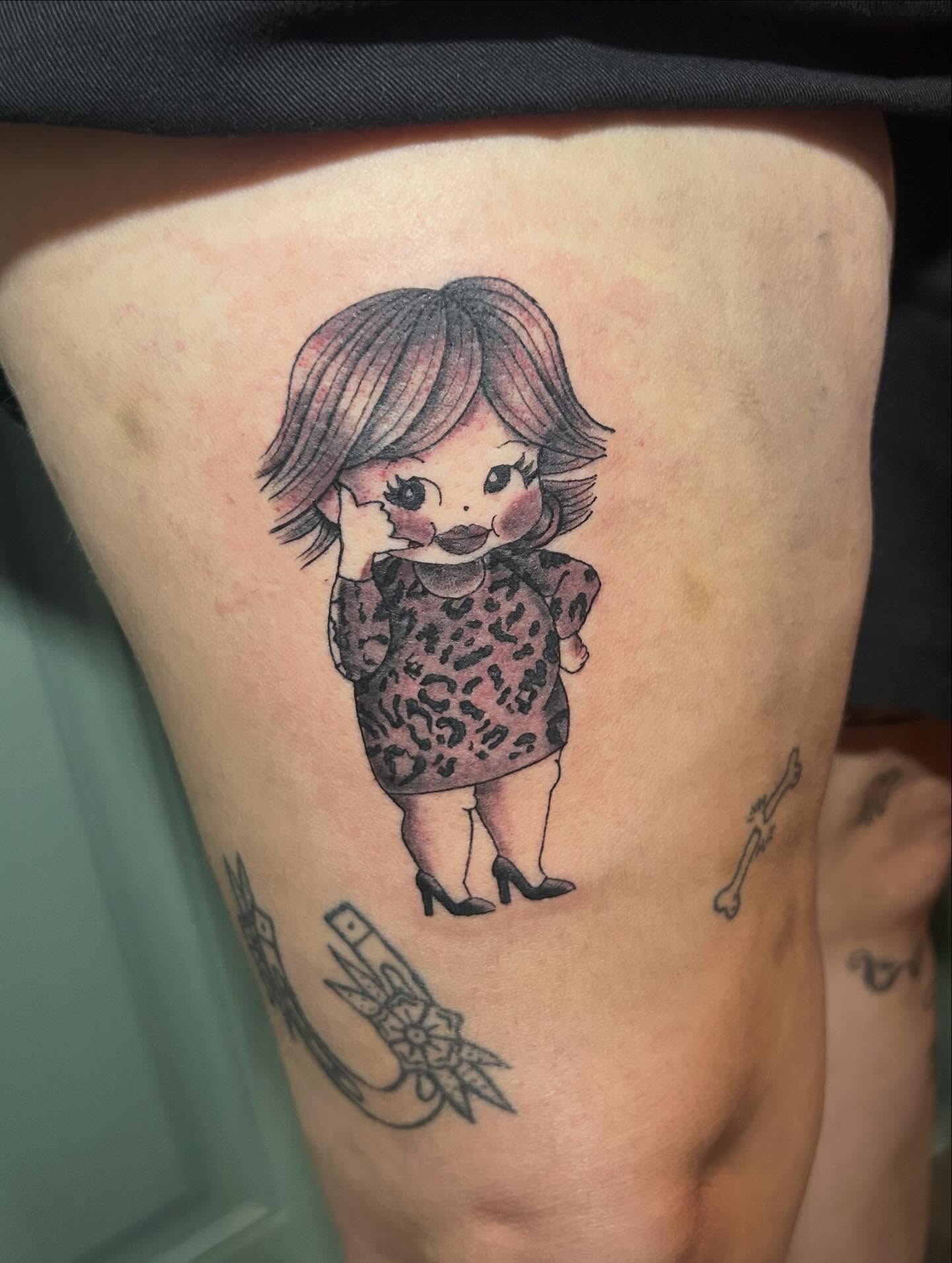 Doll illustrative tattoo on the thigh by Miss Katie