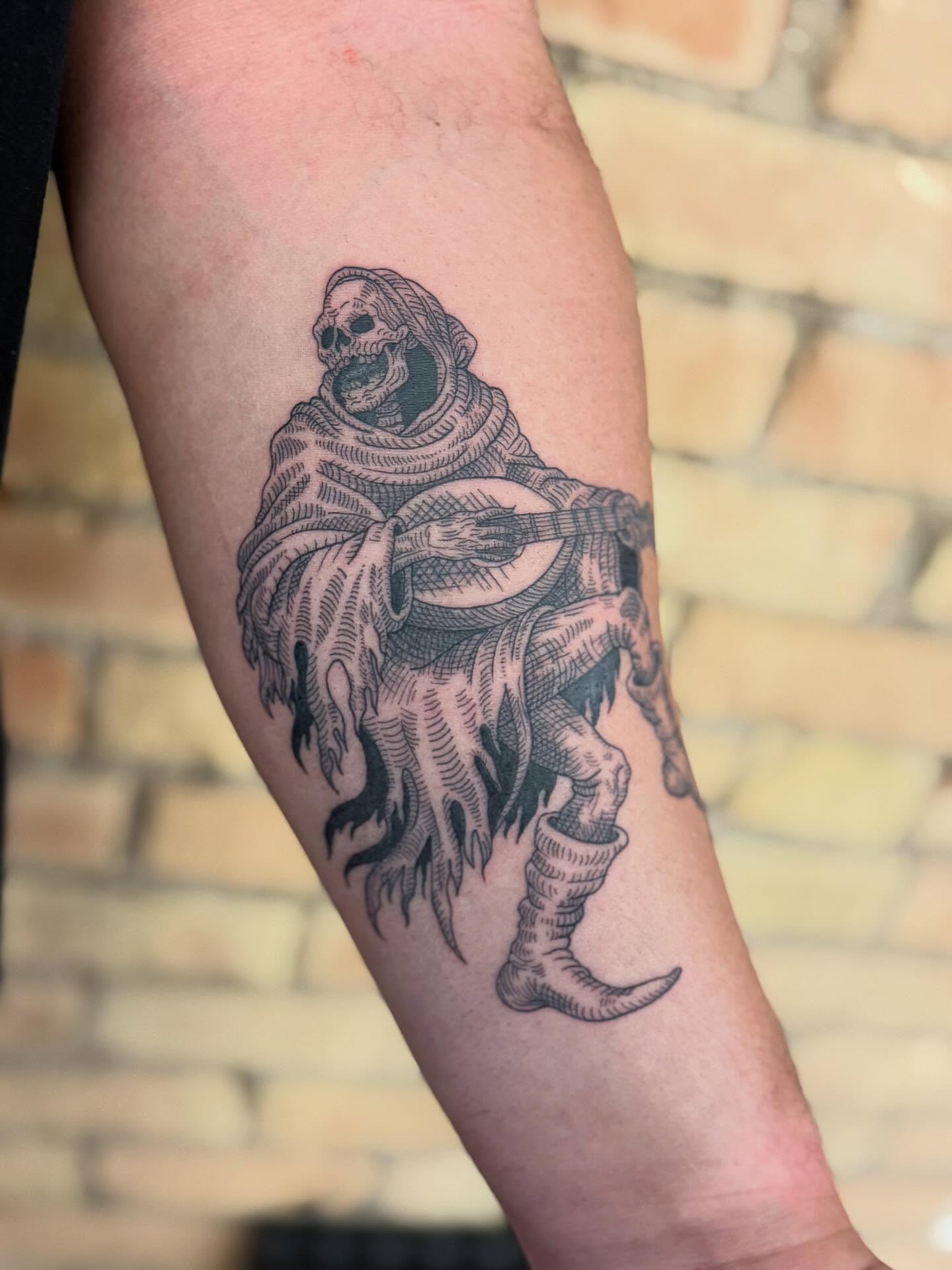 Skeleton playing guitar black and grey tattoo on the forearm by Dre