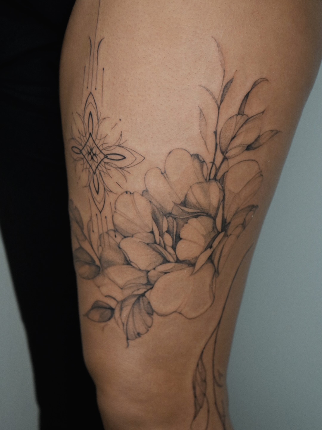 Flowers and geometric design realism tattoo on the thigh by Blackwork & microrealism tattoos
