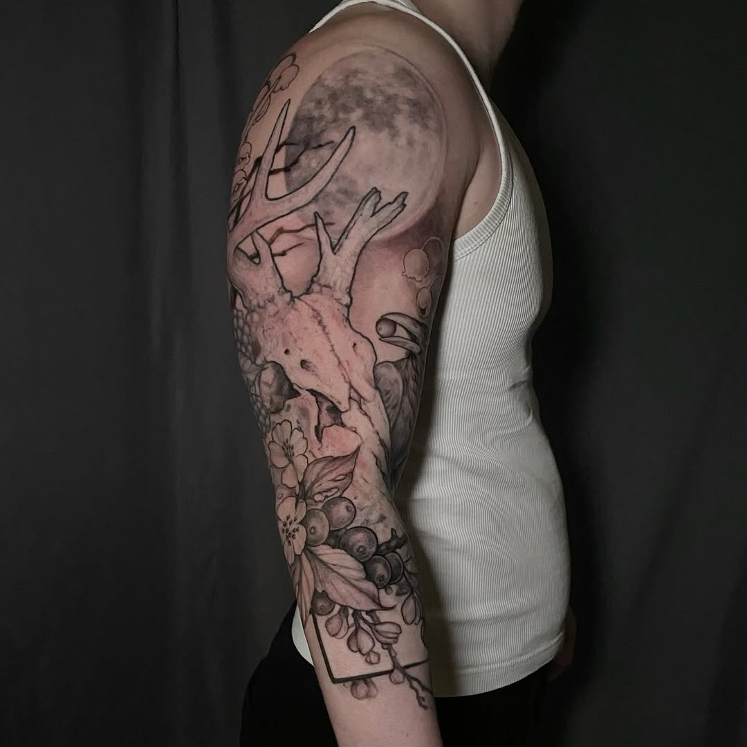 Deer skull with moon and berries realism tattoo on the forearm by Dana Jones