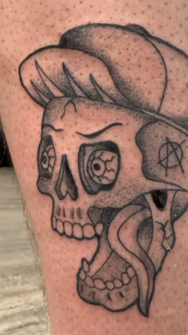 Skull with a hat and tongue realism tattoo on the leg by Matt Mahl