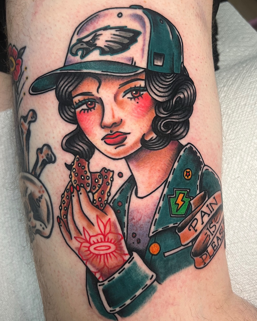 Woman wearing baseball cap American traditional tattoo on the forearm by @shannonkeeleyy