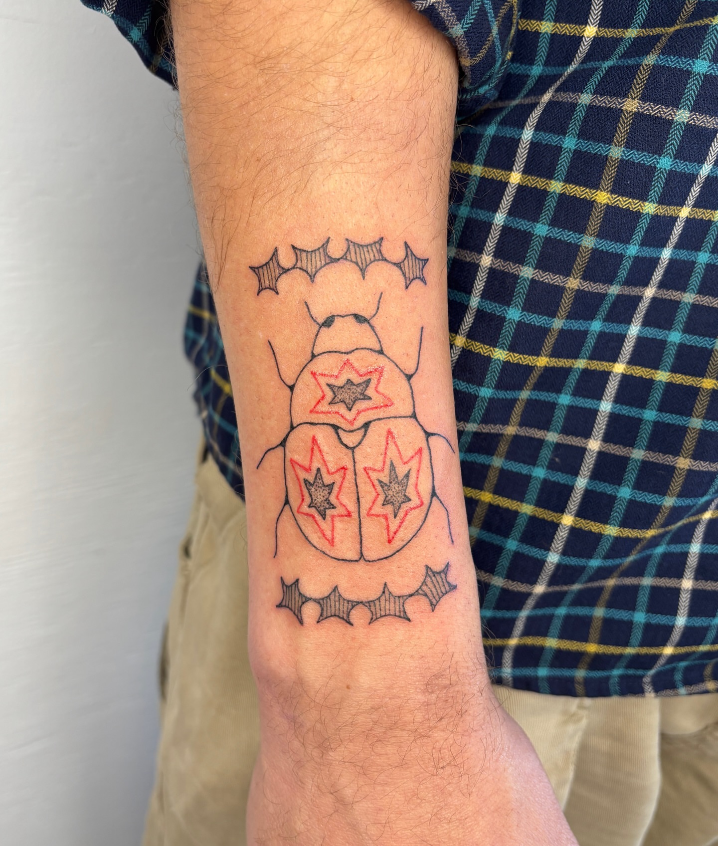 Scarab beetle geometric tattoo on the forearm by Raye
