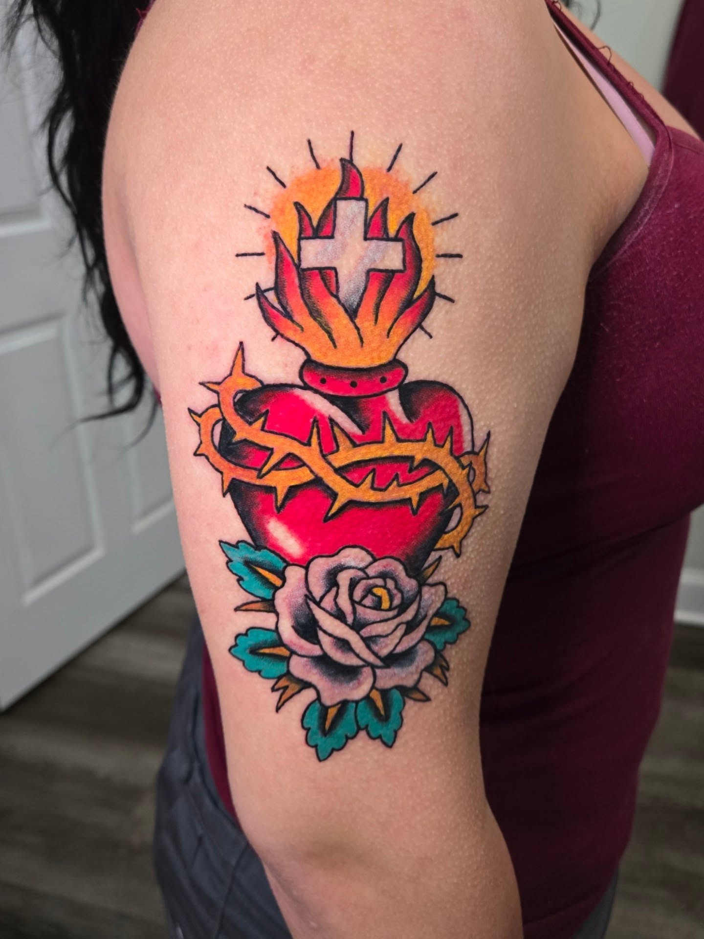 Heart and cross American traditional tattoo on the upper arm by Matt Page