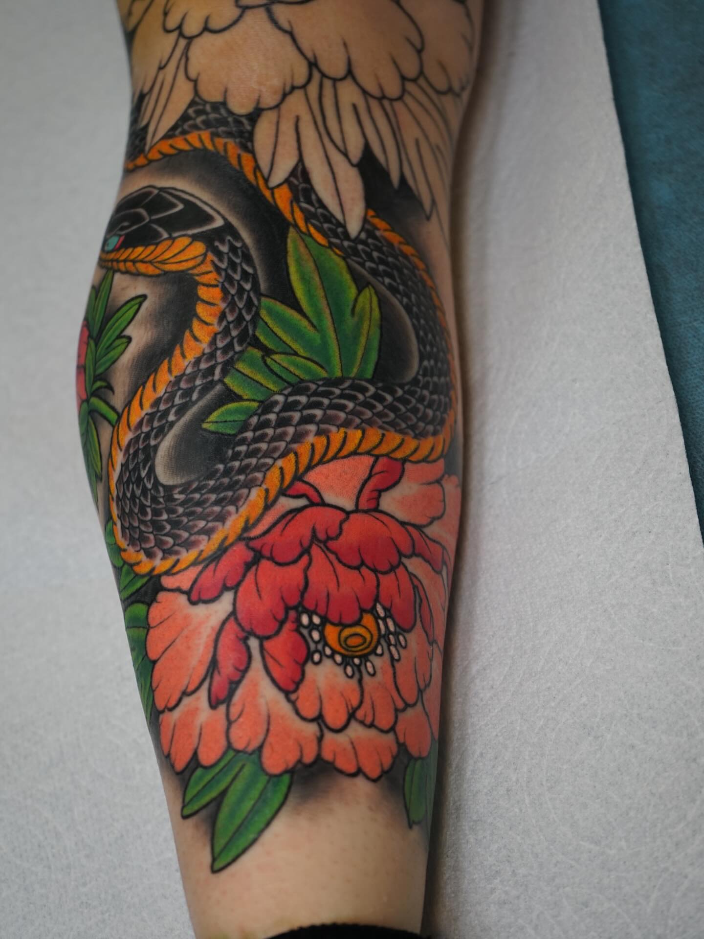 Snake and peony American traditional tattoo on the forearm by Tyler Harrington