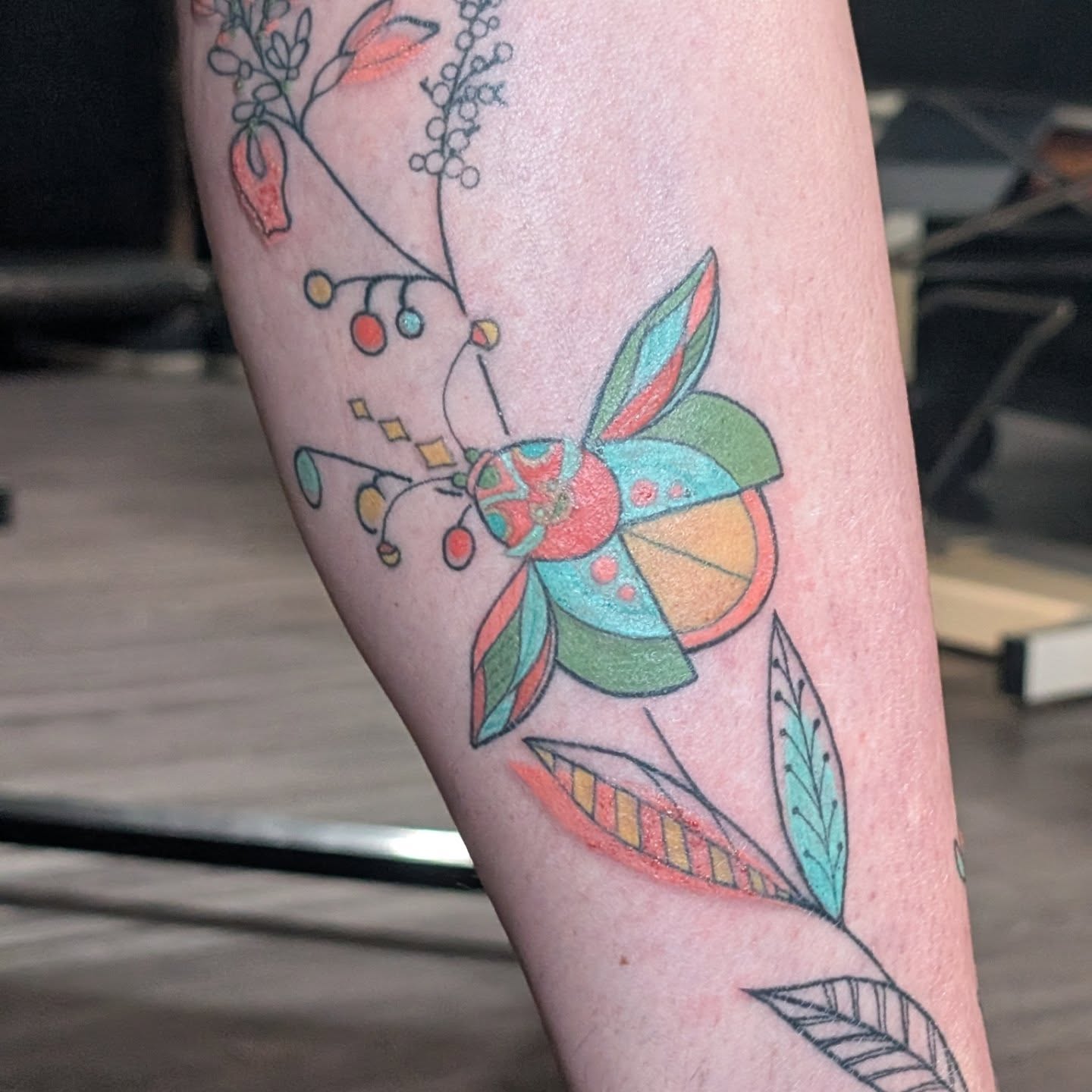 Insect and floral new school tattoo on the forearm by Michaela May