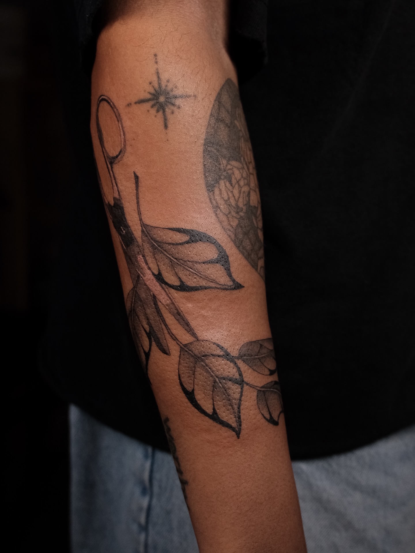Umbrella and leaves black and grey tattoo on the forearm by Kiana Hope