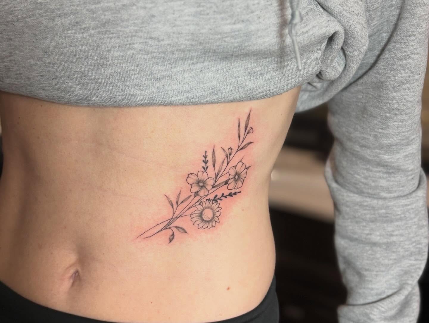 Floral arrangement fine line tattoo on the ribs by Tessa Simmons - Tattoo Artist