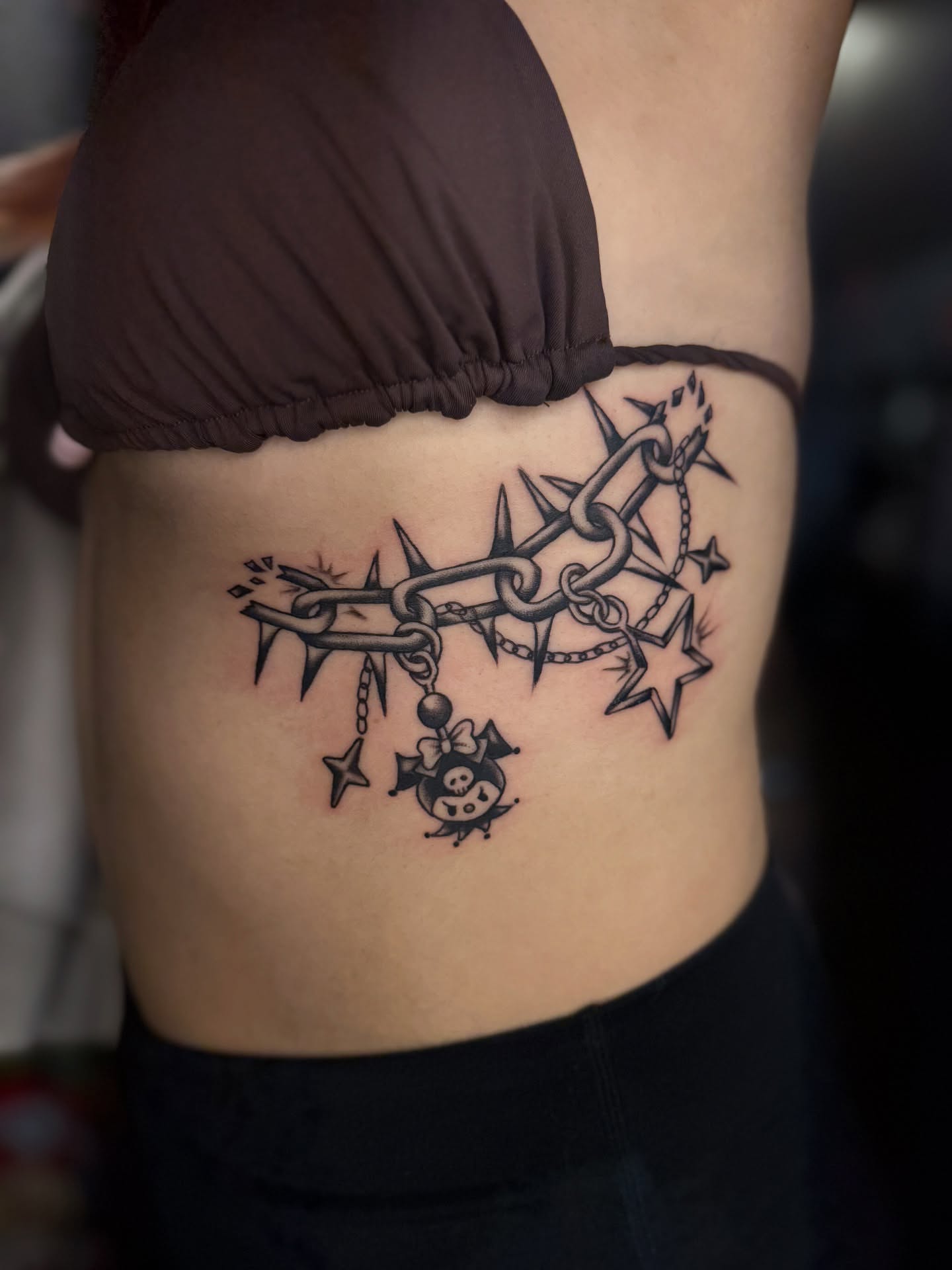 Barbed chain with stars black and grey tattoo on the ribs by Sarah Pham