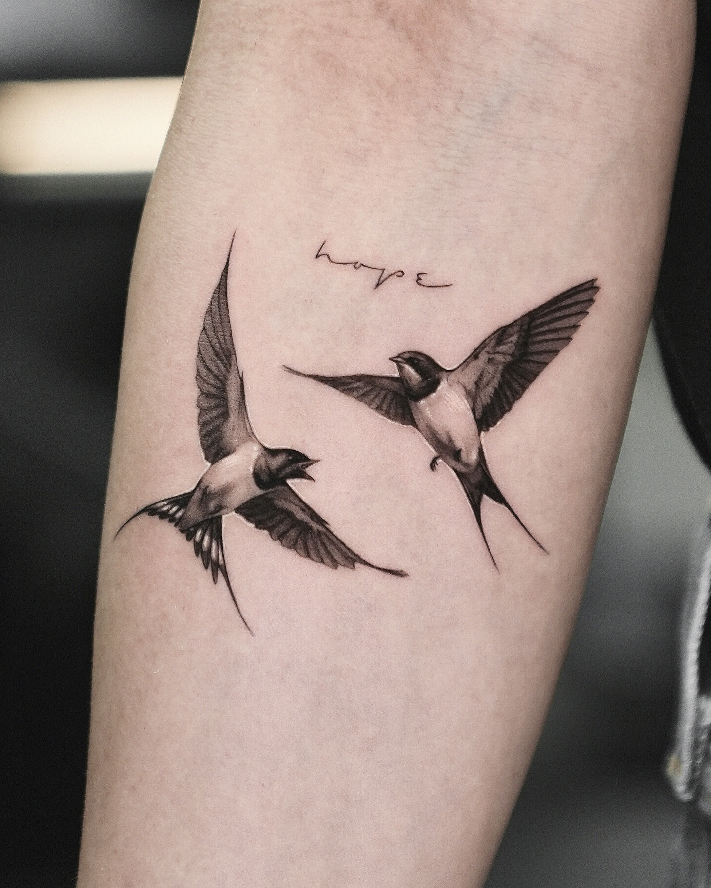 Swallows black and grey tattoo on the forearm by Kid Needle