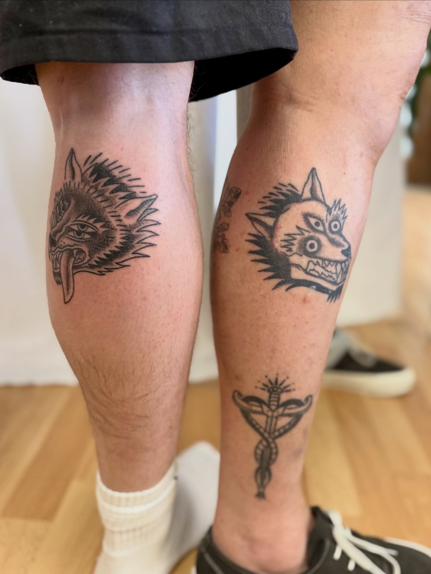 Wolf heads black and grey tattoo on the calf by Melia Mariko