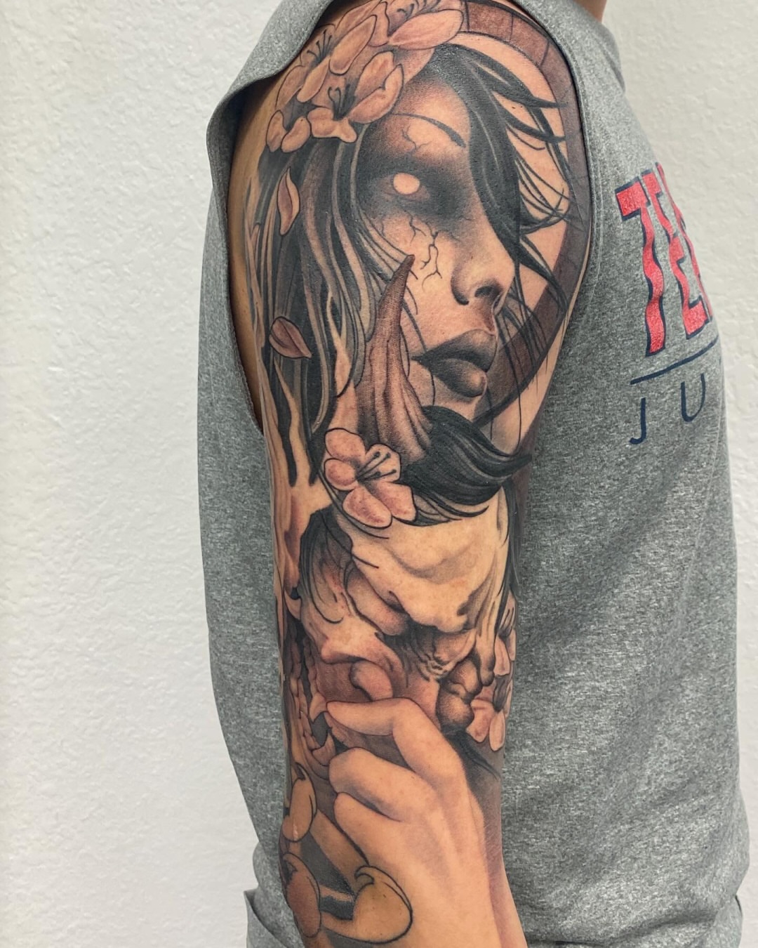 Woman with flowers realism tattoo on the upper arm by Mike Nance