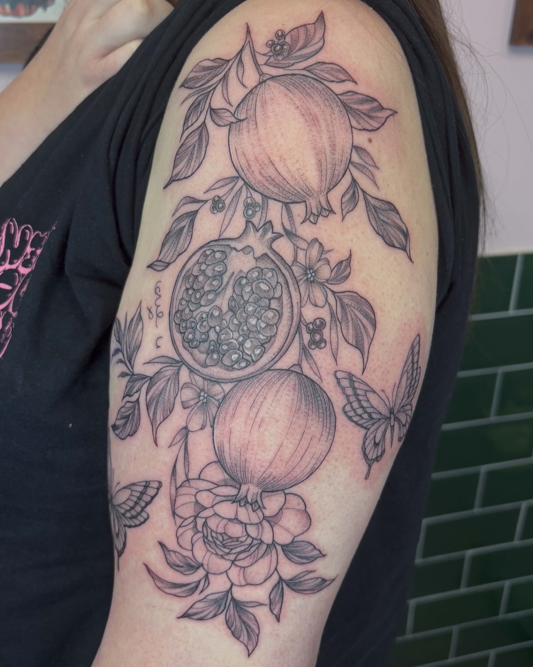 Pomegranate and flowers realism tattoo on the shoulder by Mike Nance
