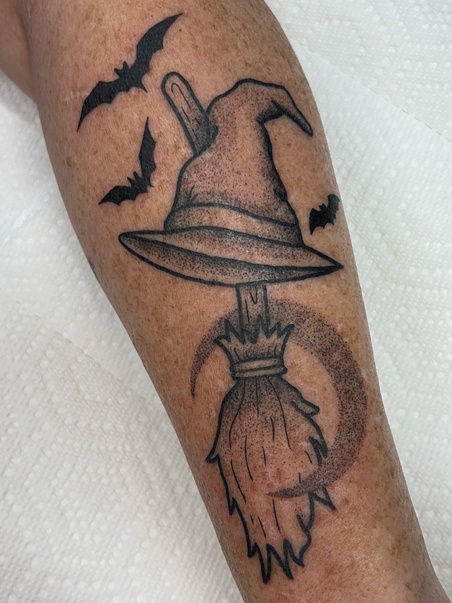 Witch hat and broom black and grey tattoo on the forearm by 𝑴𝒂𝒚𝒂𖤐𝑫𝒆𝑽𝒊𝒏𝒆, Dayton, Ohio
