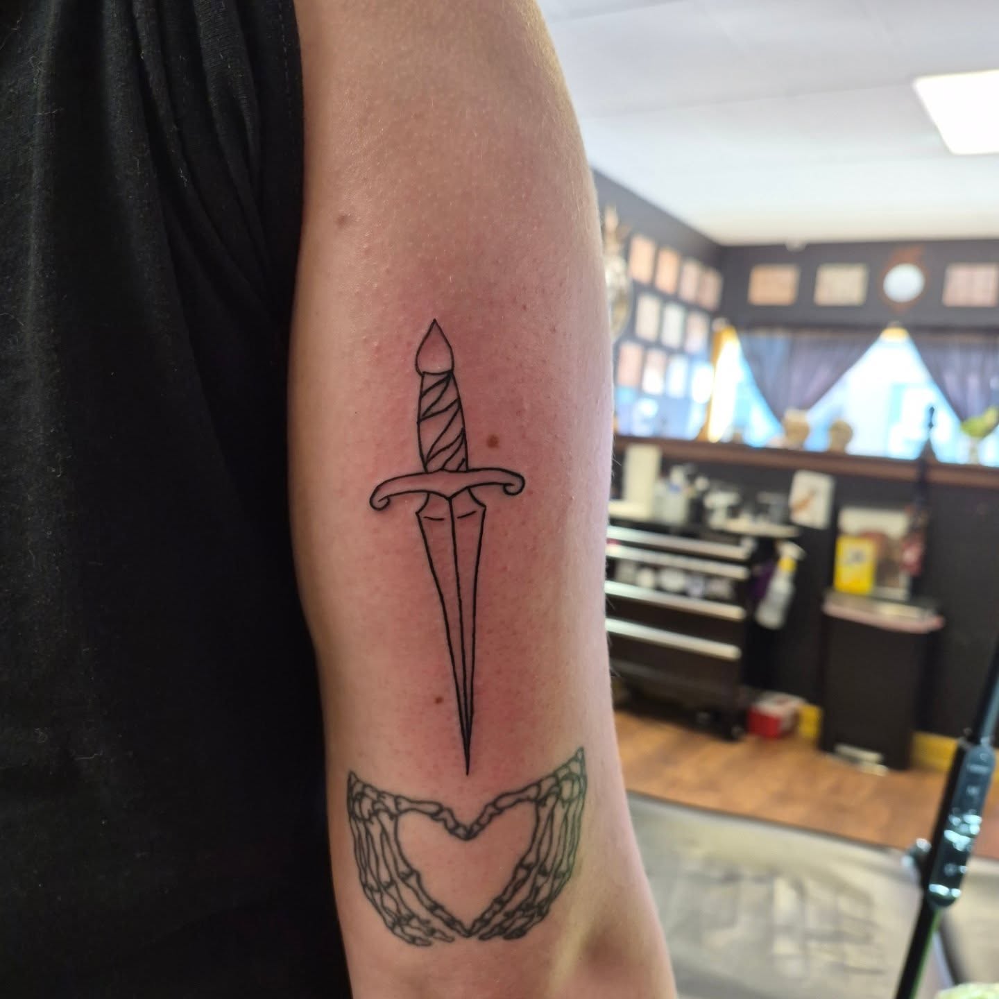 Sword and heart black and grey tattoo on the forearm by Bobby H