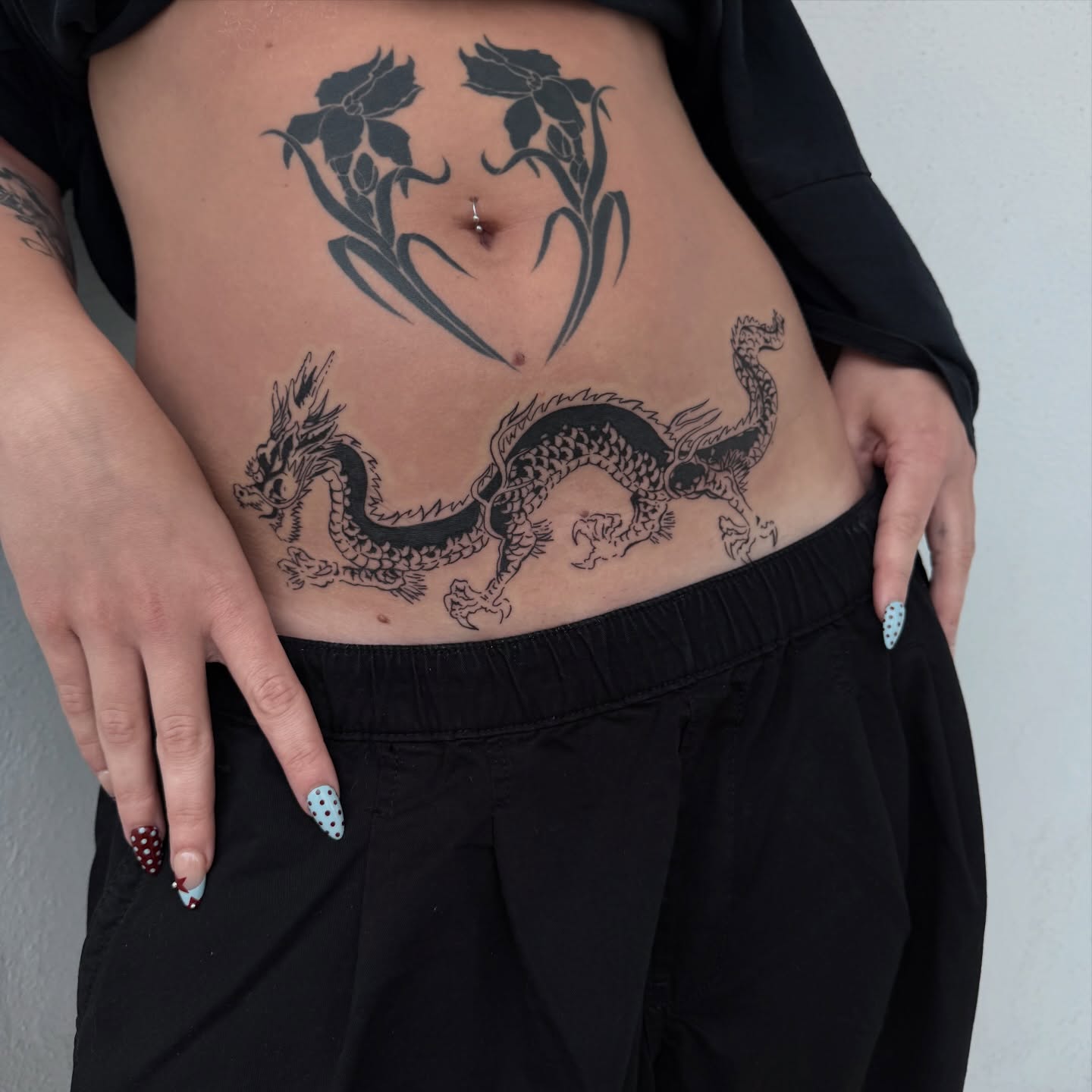 Dragon and floral heart black and grey tattoo on the torso by Sophia Tattoo