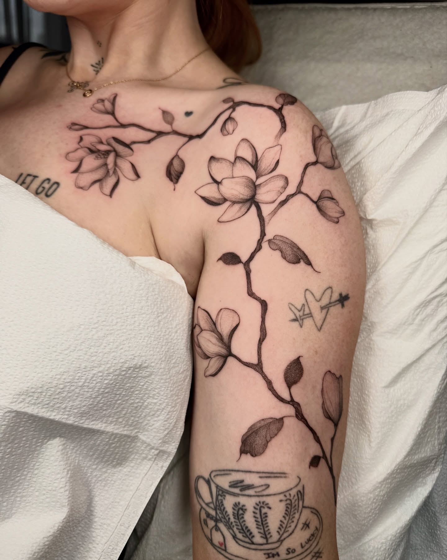 Flower branch black and grey tattoo on the upper arm by Molly Murray
