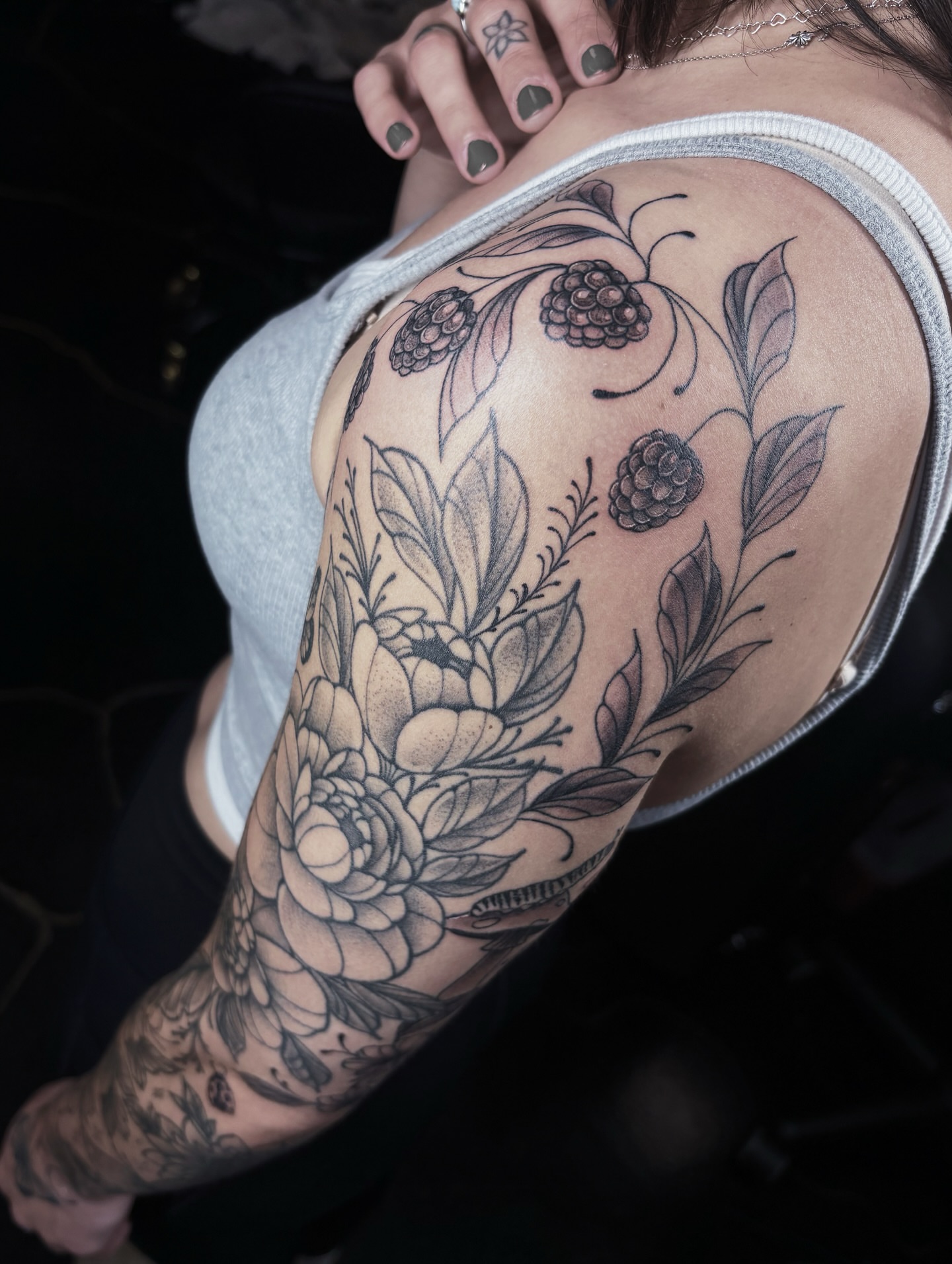 Floral arrangement black and grey tattoo on the upper arm by Fine Line Tattoo Artist