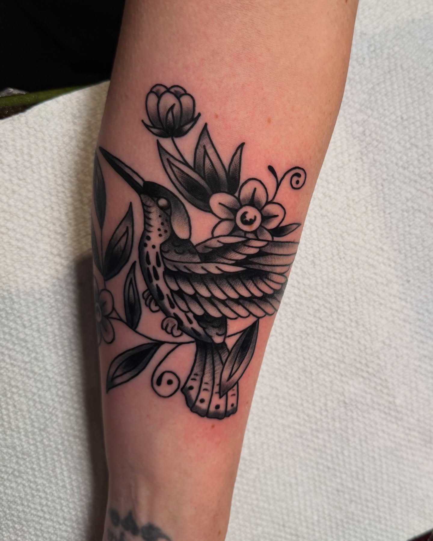 Hummingbird and flowers American traditional tattoo on the forearm by πππ’π―π’π¨ πππΆπ©π¬π―π, Manchester, New Hampshire