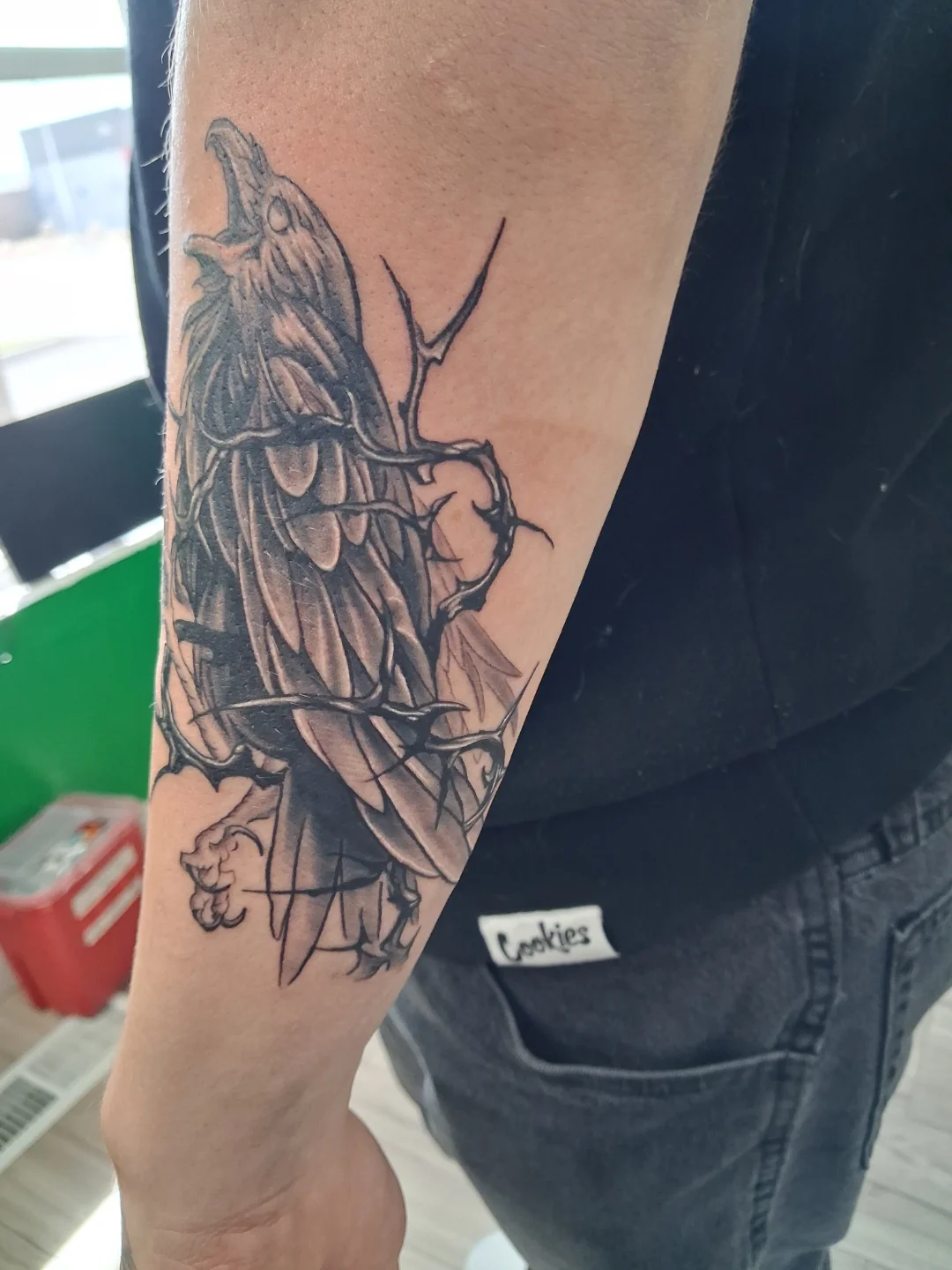 Raven black and grey tattoo on the forearm by James Ostler