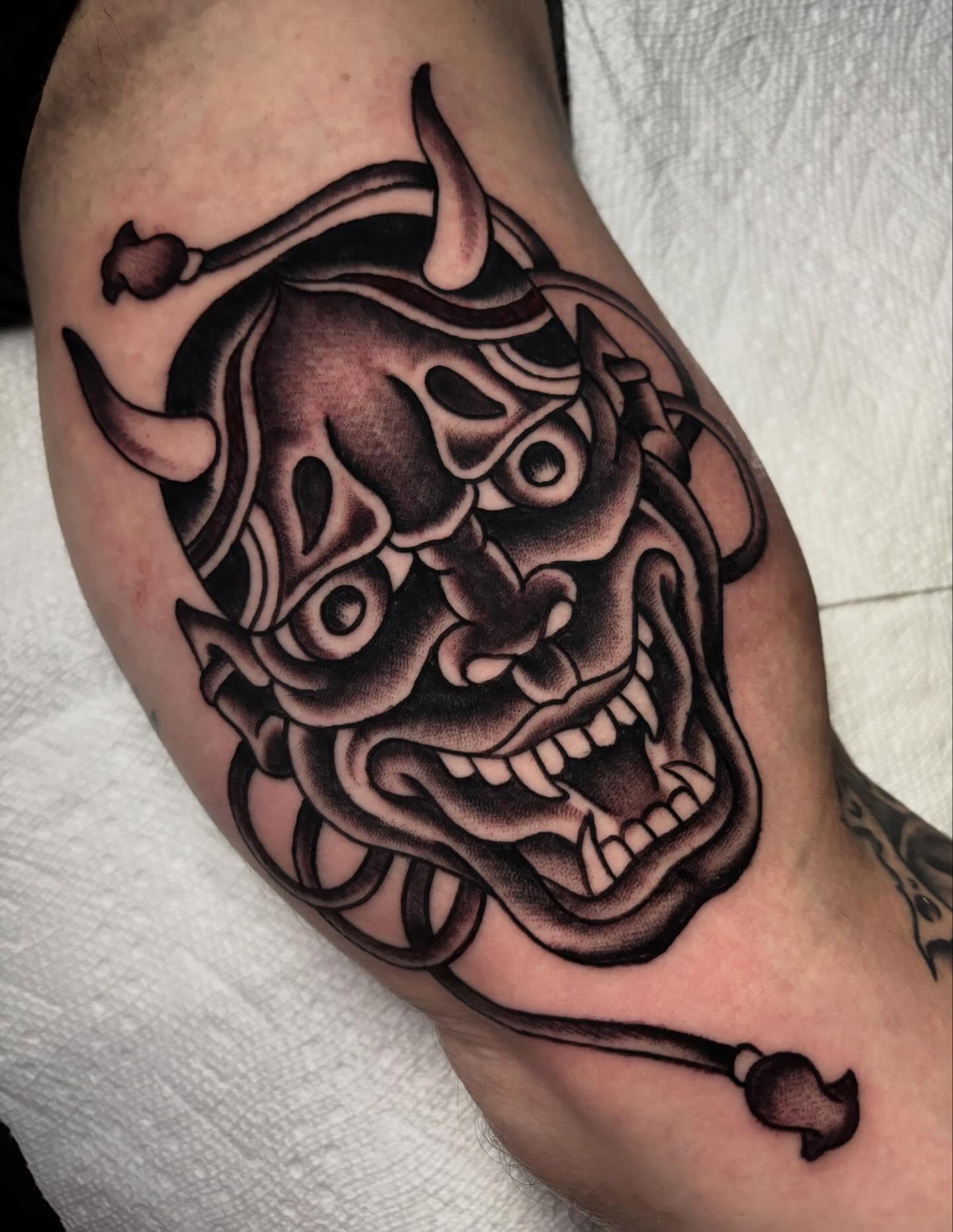 Demon mask black and grey tattoo on the forearm by Chris Dufresne