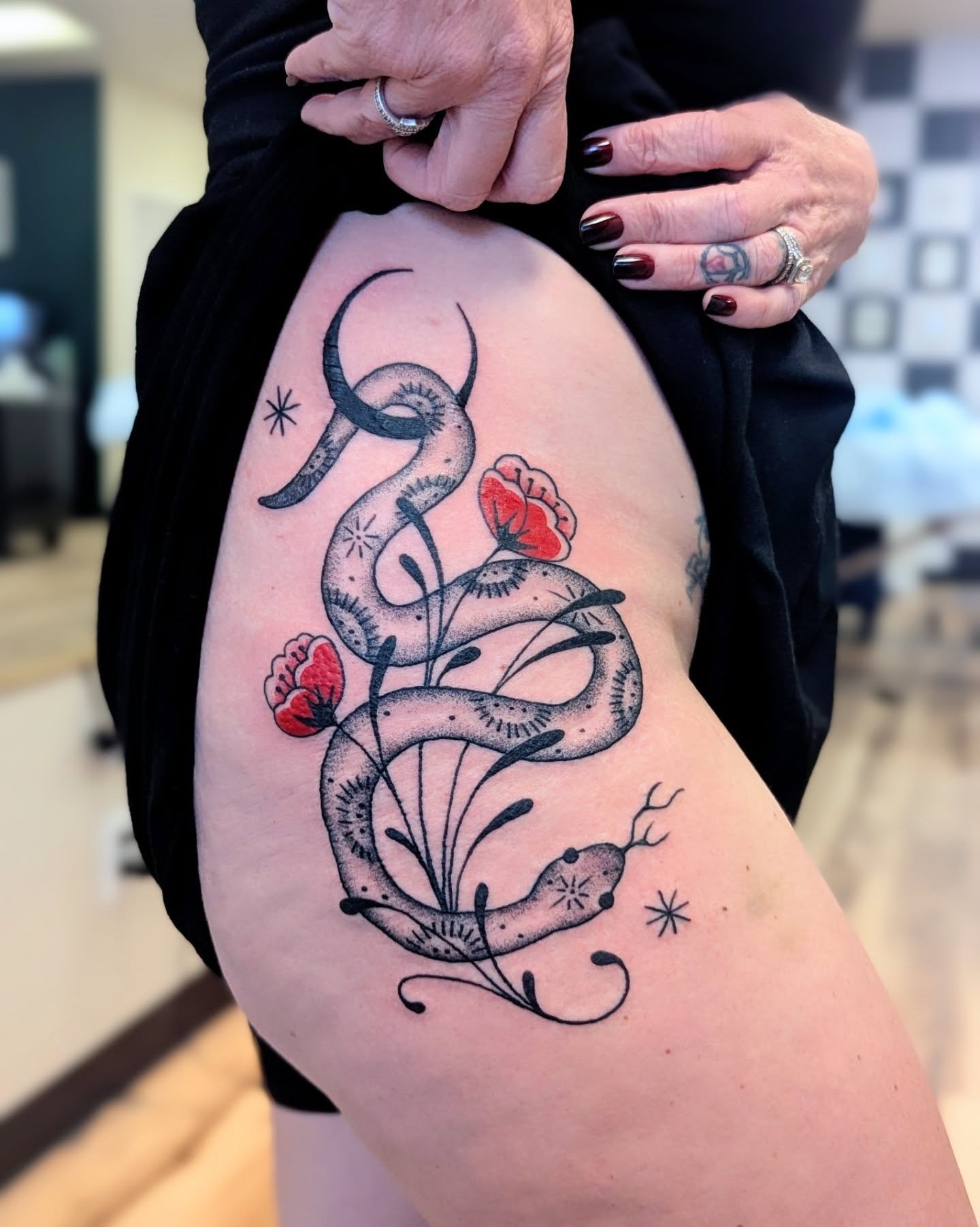 Snake and flowers black and grey tattoo on the thigh by Dani Harkey
